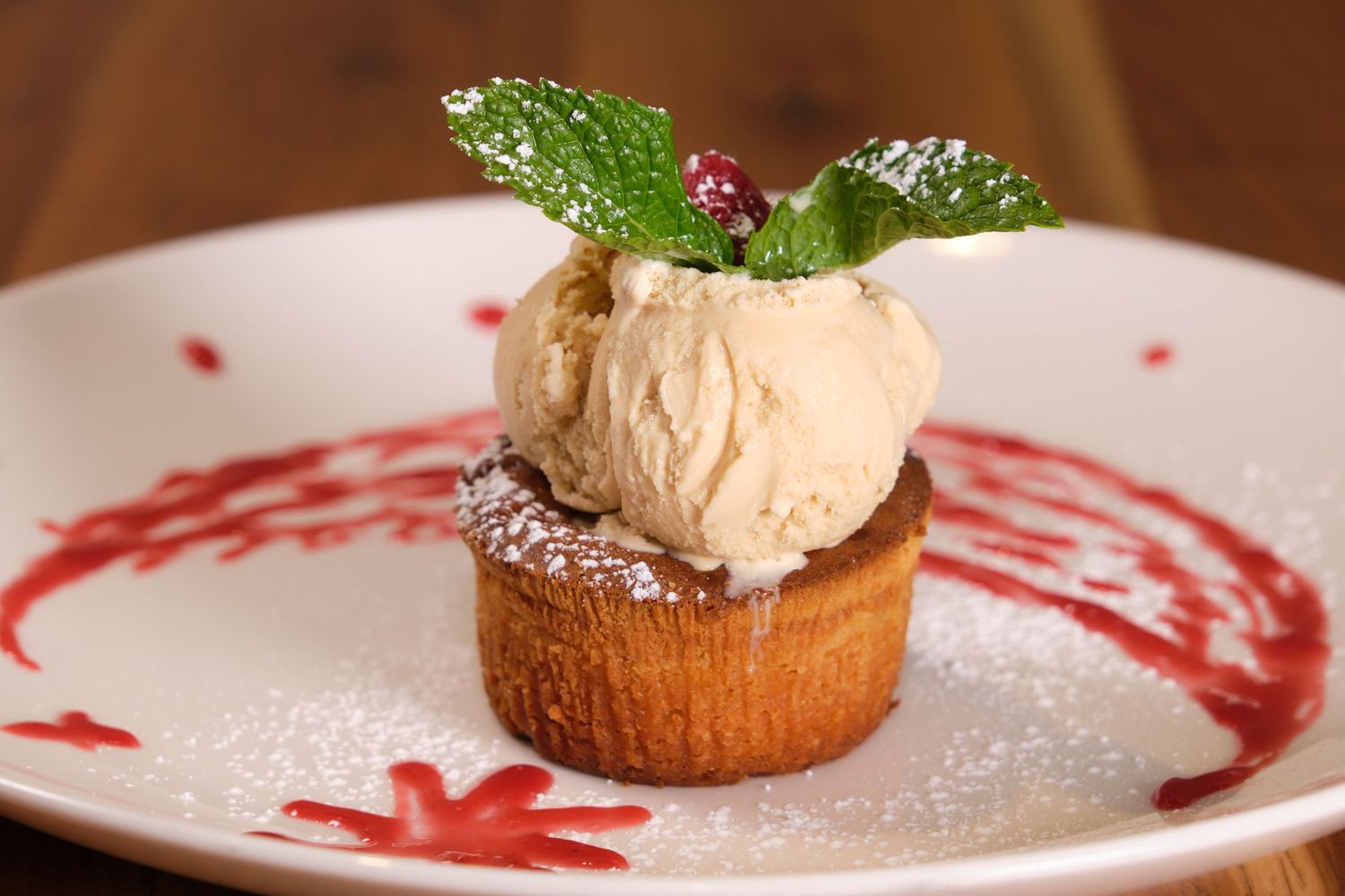 Dessert plate featuring ice cream on a pastry base with mint and raspberry sauce.