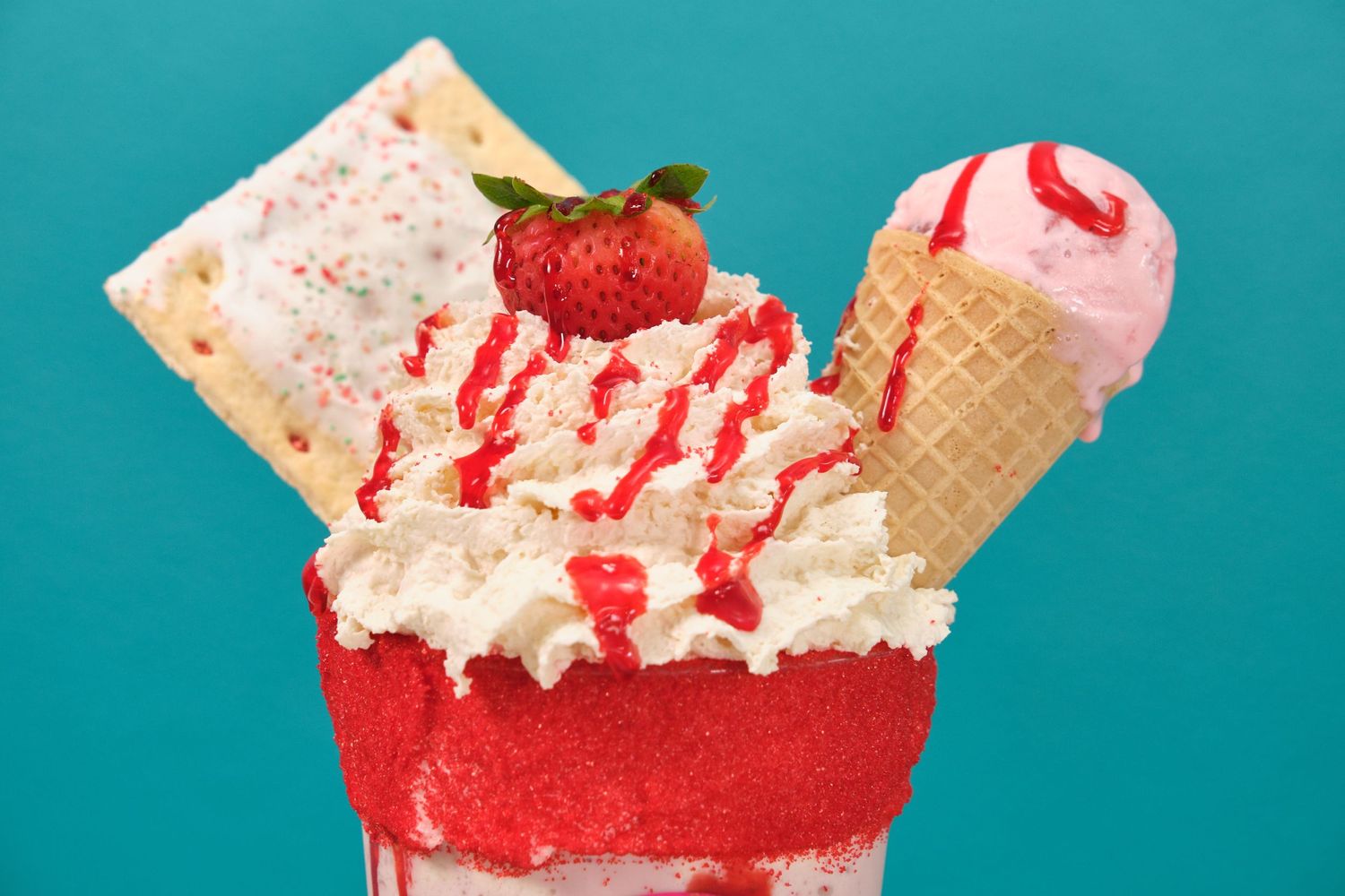 Red and white ice cream sundae with strawberry, wafer, and cone toppings against turquoise background.
