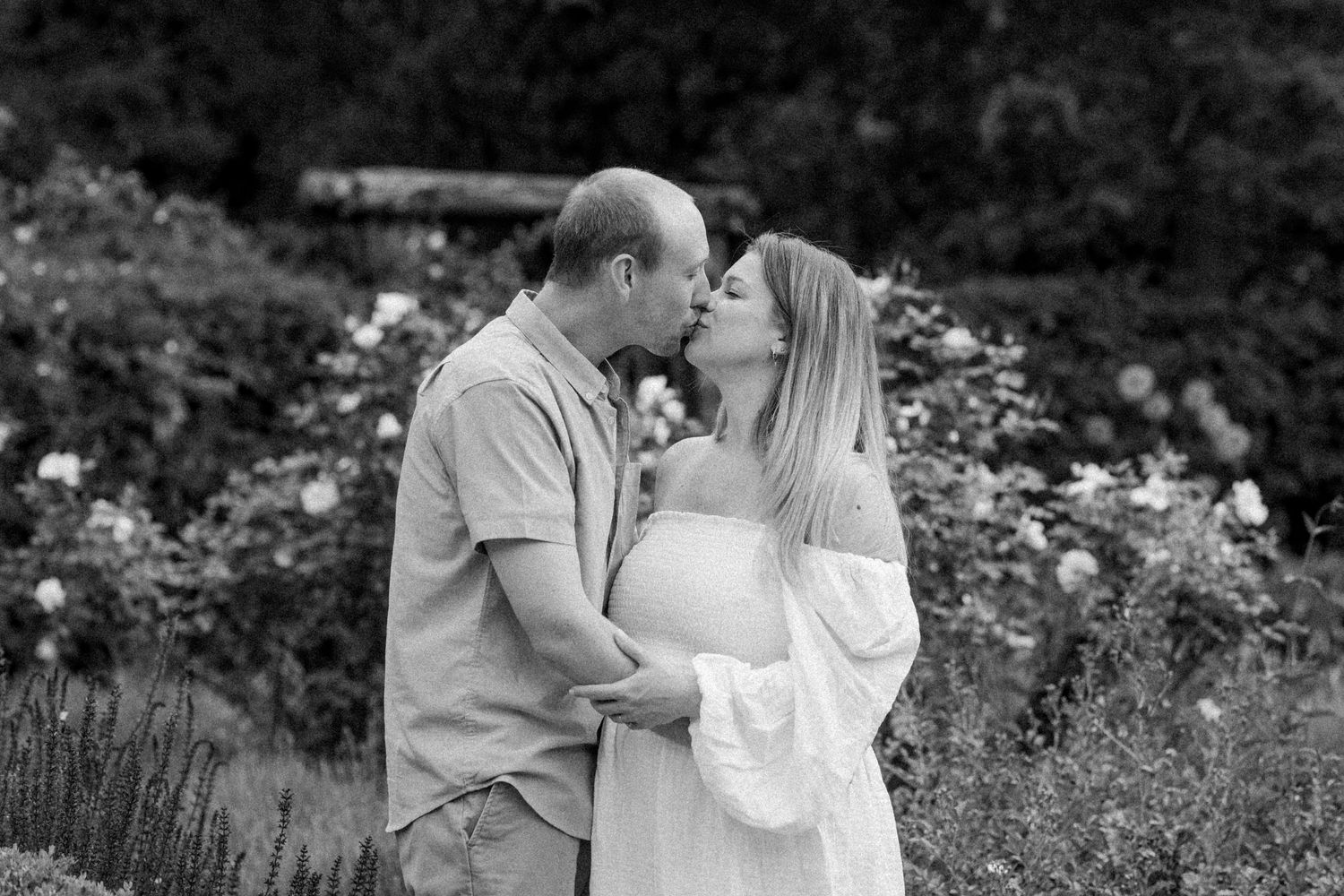 Black and white romantic portrait of a couple in a flower garden.