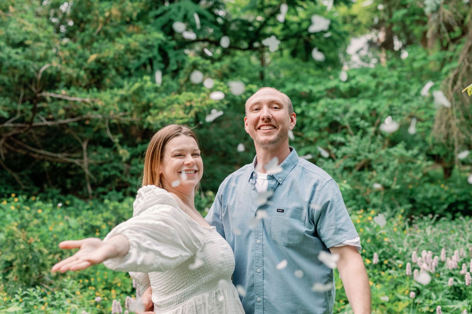 A couple laughs and celebrates together in a verdant garden setting.