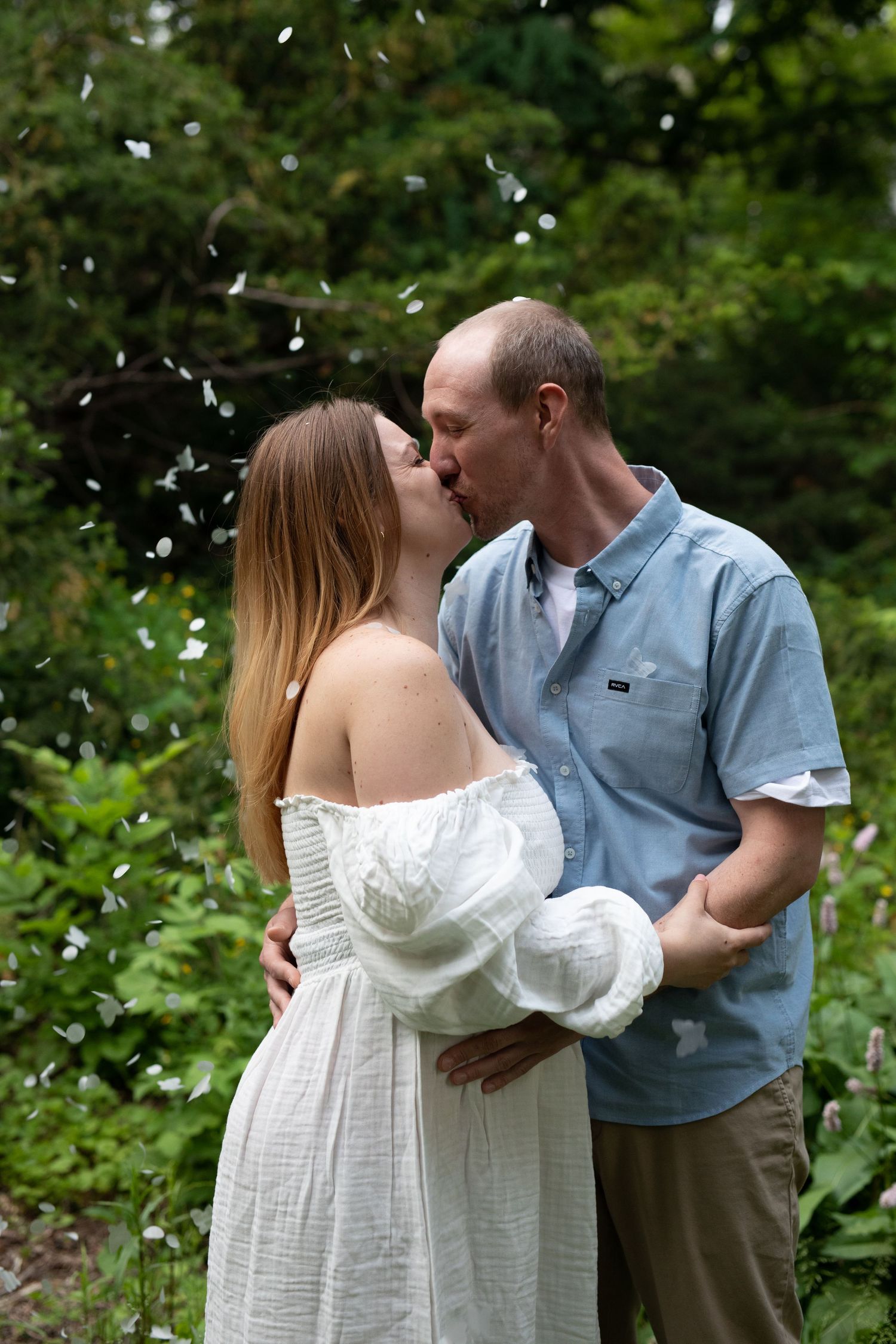 A romantic garden scene with a couple embracing as confetti falls around them.