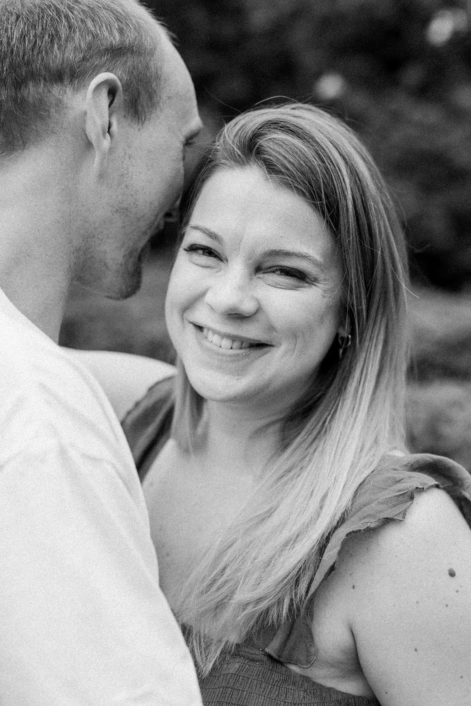 Close-up black and white photos capturing candid laughter and tender moments between a couple.