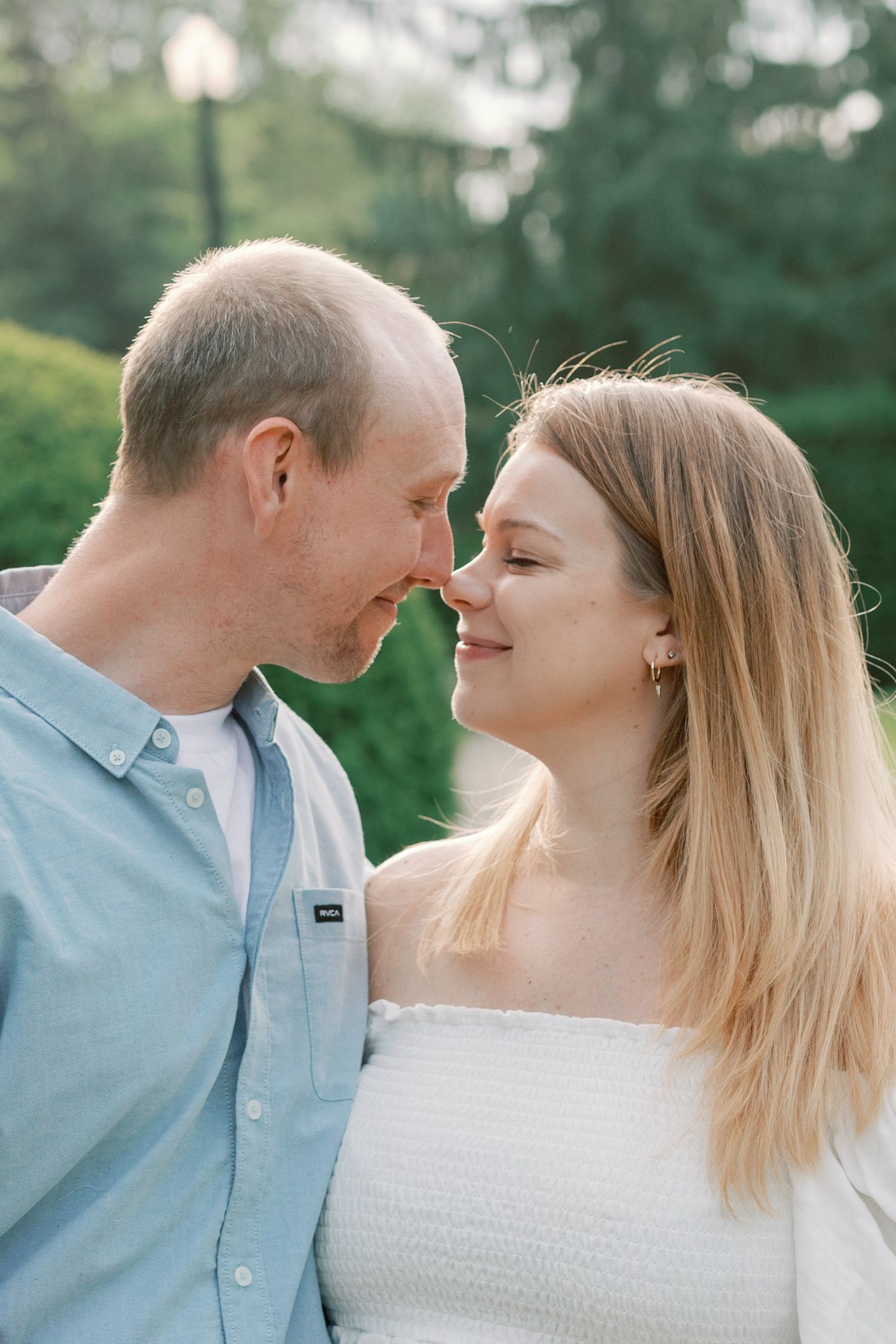 A couple in coordinating blue and white outfits share tender moments in a garden setting.