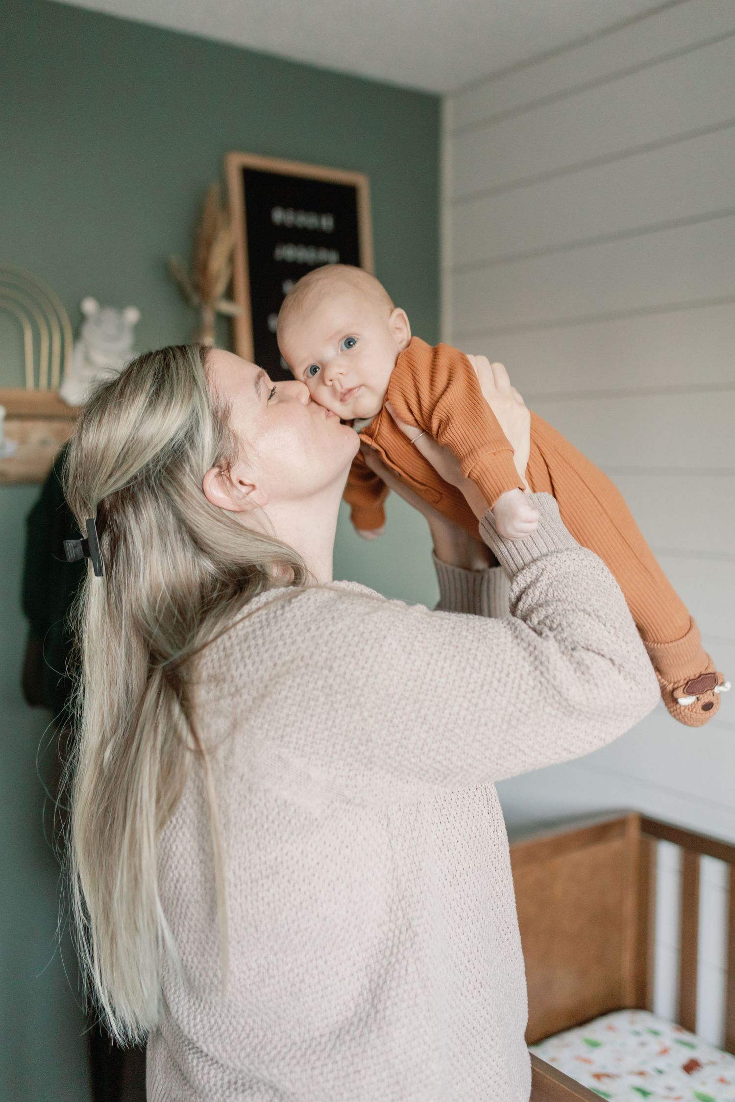 A new mother lifts her newborn up into the air, kissing him on the cheek. Photo by Katie Crane Photography.