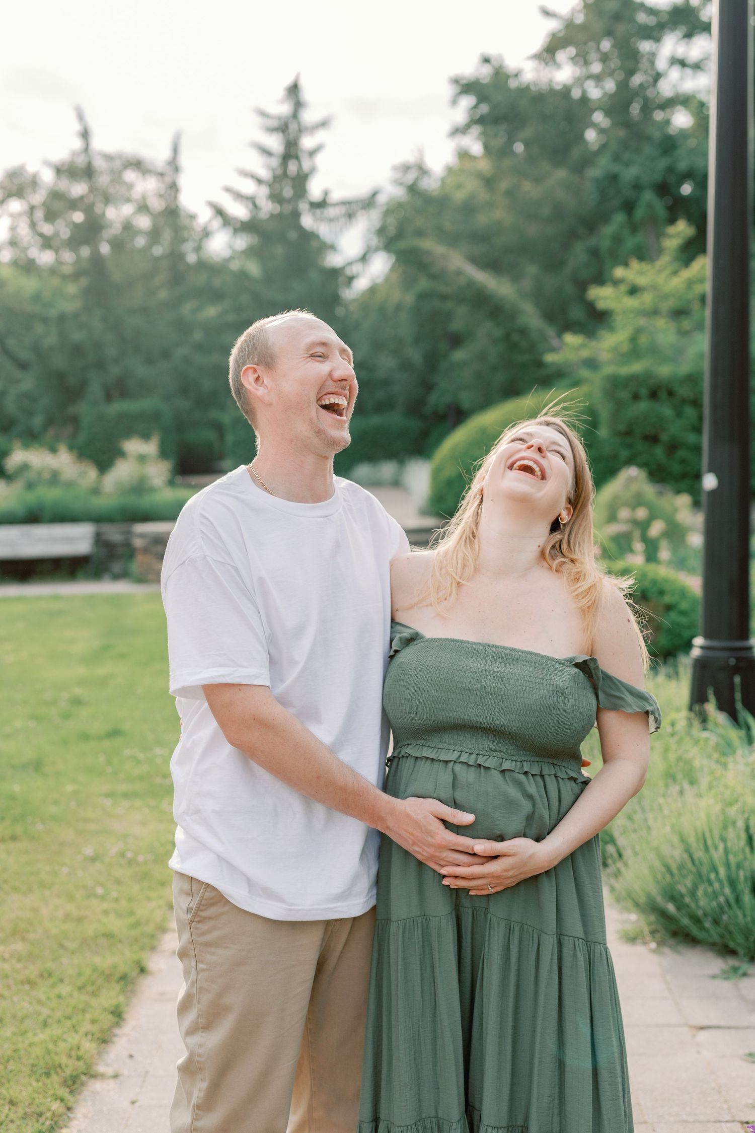 A couple laughs together during a photo session in a scenic garden landscape.