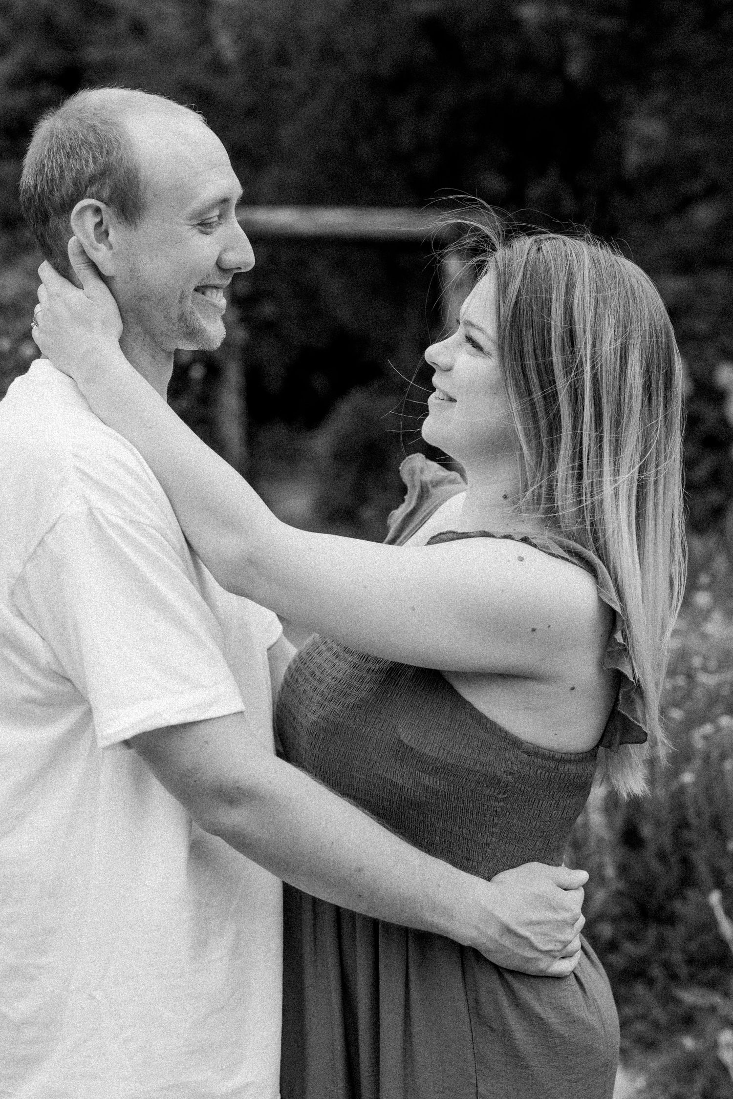 A romantic black and white photo series showing a couple embracing and laughing together outdoors.