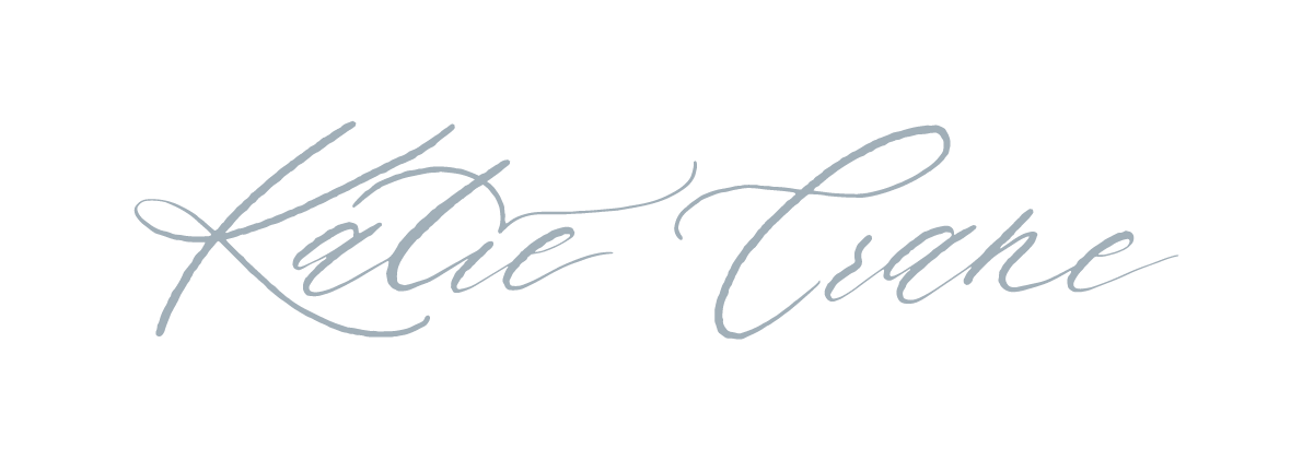 Elegant cursive signature in gray ink on white paper.
