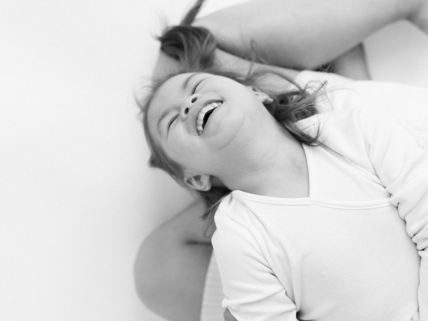 Black and white close-up of joyful toddler laughing on mom's lap at Velvet Season Studios in Ajax - Katie Crane, Candid 