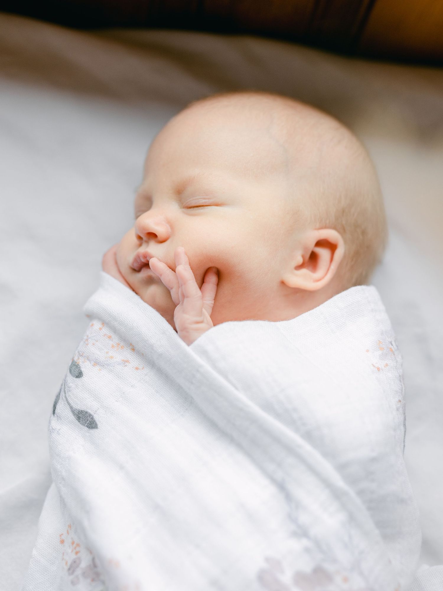 Peaceful sleeping newborn wrapped in soft white blanket.