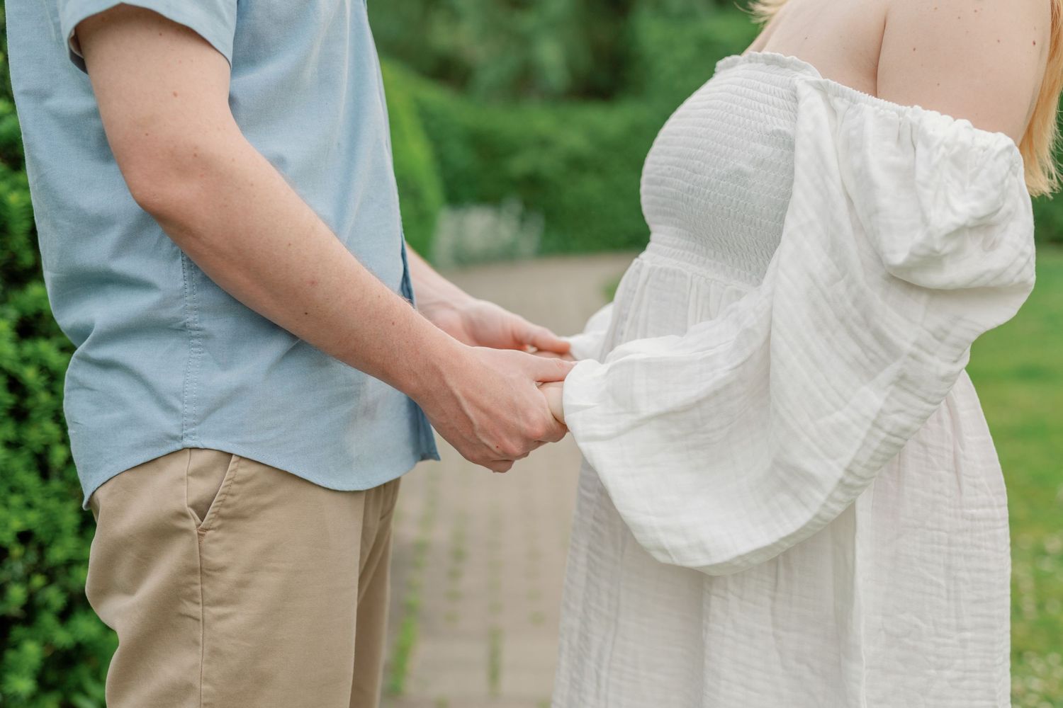 Couple in casual attire embracing outdoors in a garden setting.