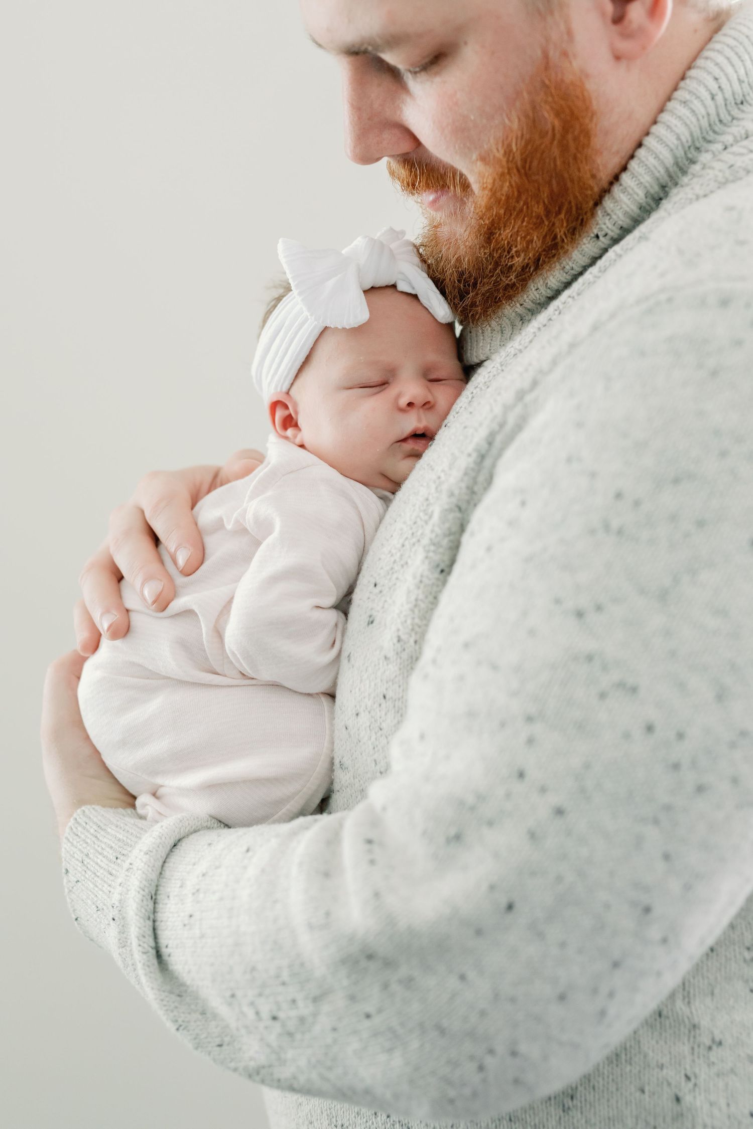 A man holds his newborn against his chest while she sleeps. Photo by Katie Crane Photography.