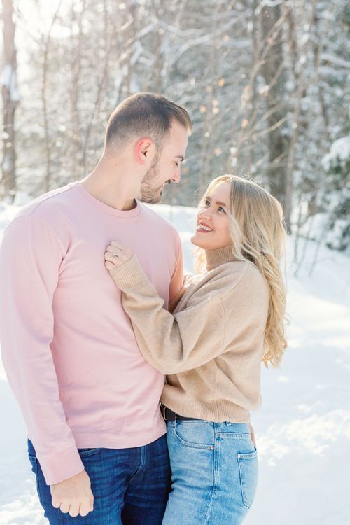 Couple sharing playful moments in a snowy winter forest setting.