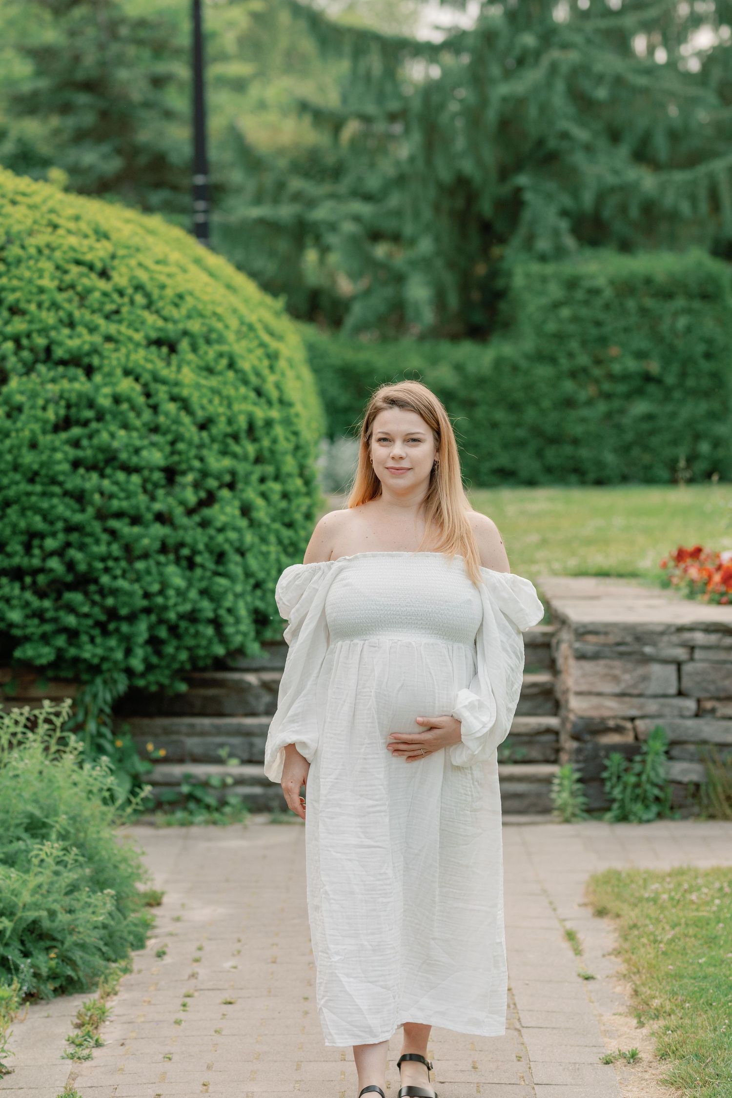 A series of maternity photos taken in a beautiful garden setting with stone pathways.