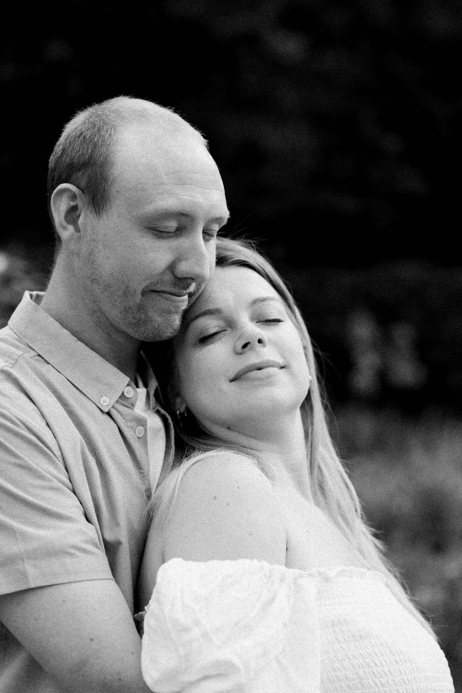 A romantic black and white portrait of a couple sharing an intimate moment in nature.