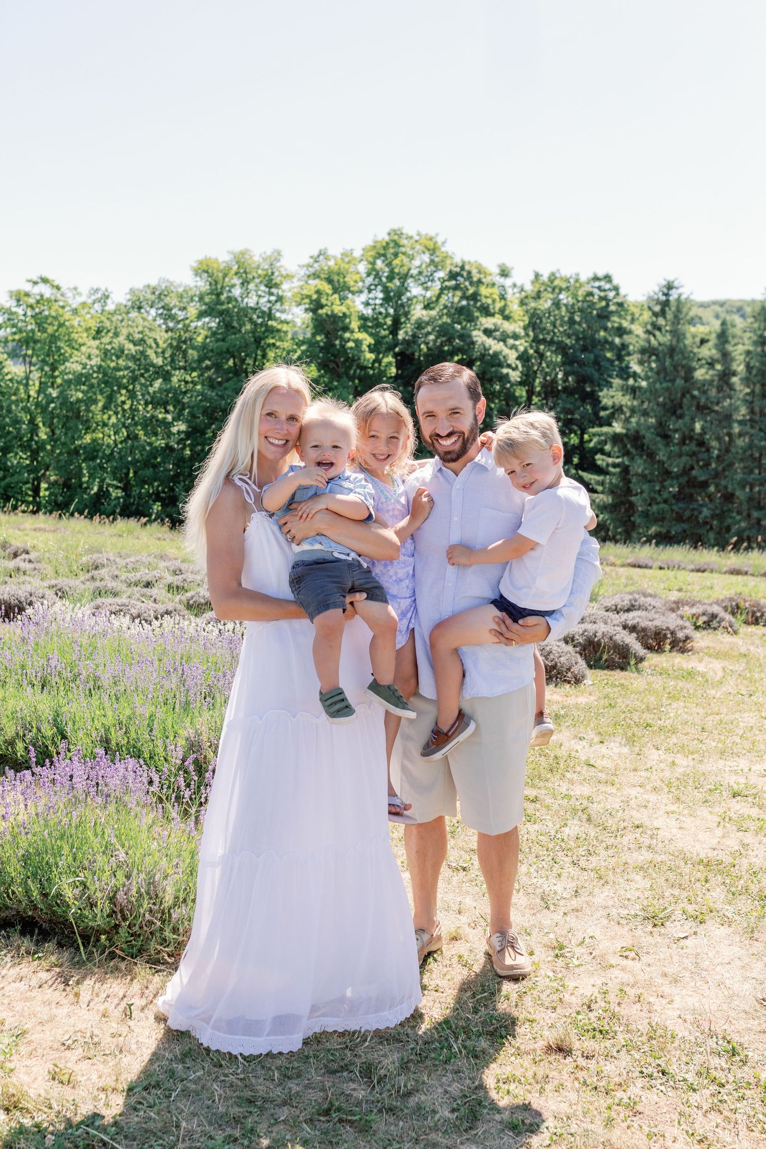 Family portrait in summer field with lavender flowers and natural lighting.