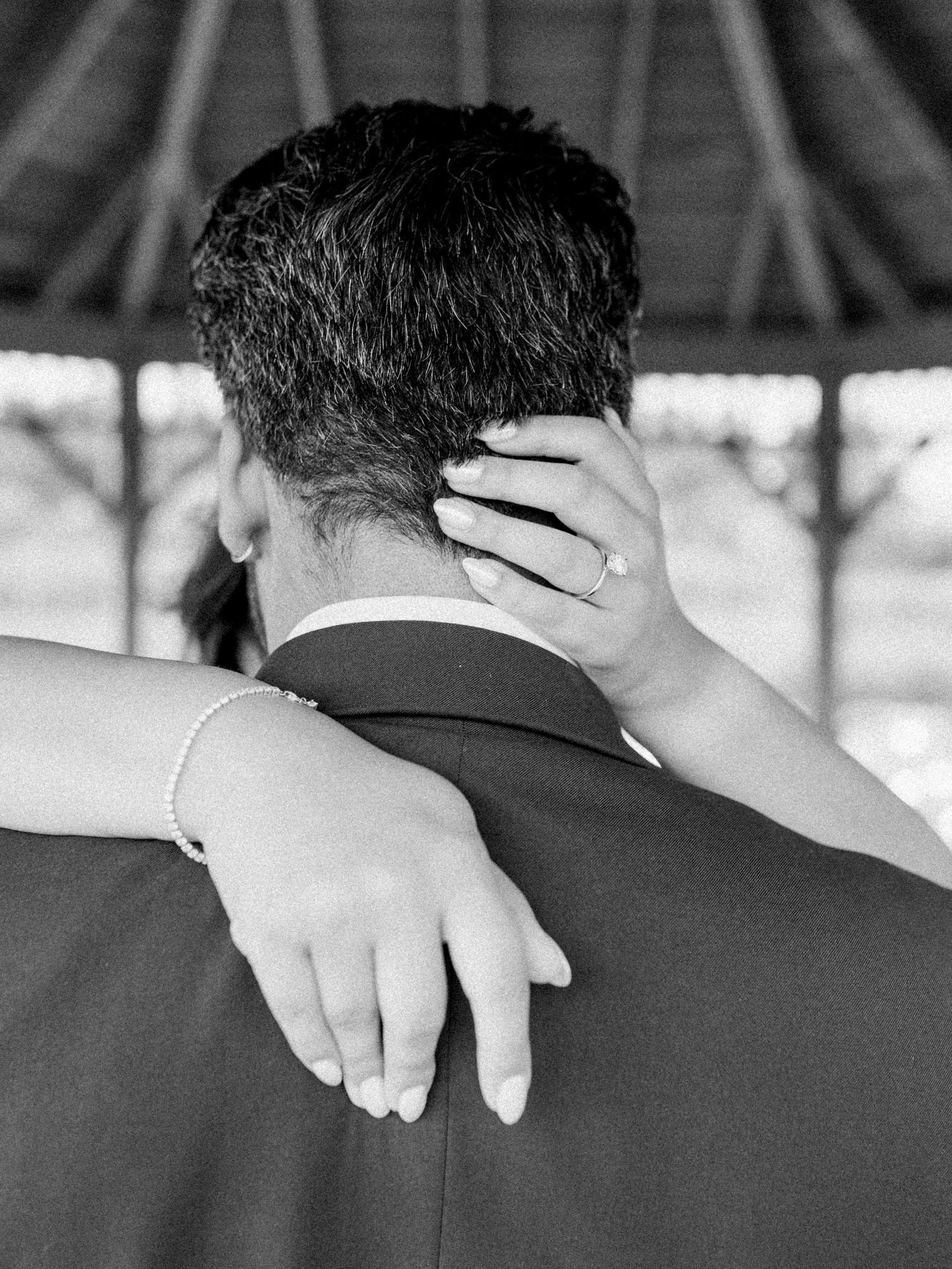 A close-up black and white shot shows hands resting tenderly on shoulders during a romantic moment.