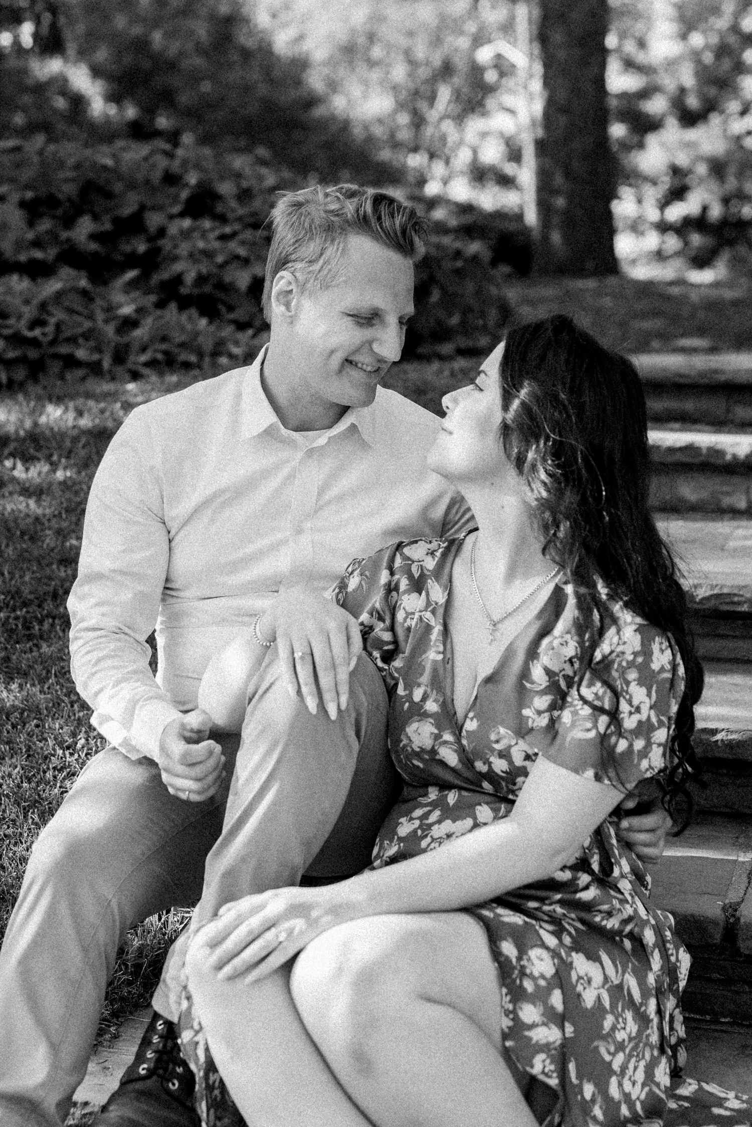Romantic couple sharing intimate moment while sitting outdoors in black and white photography.