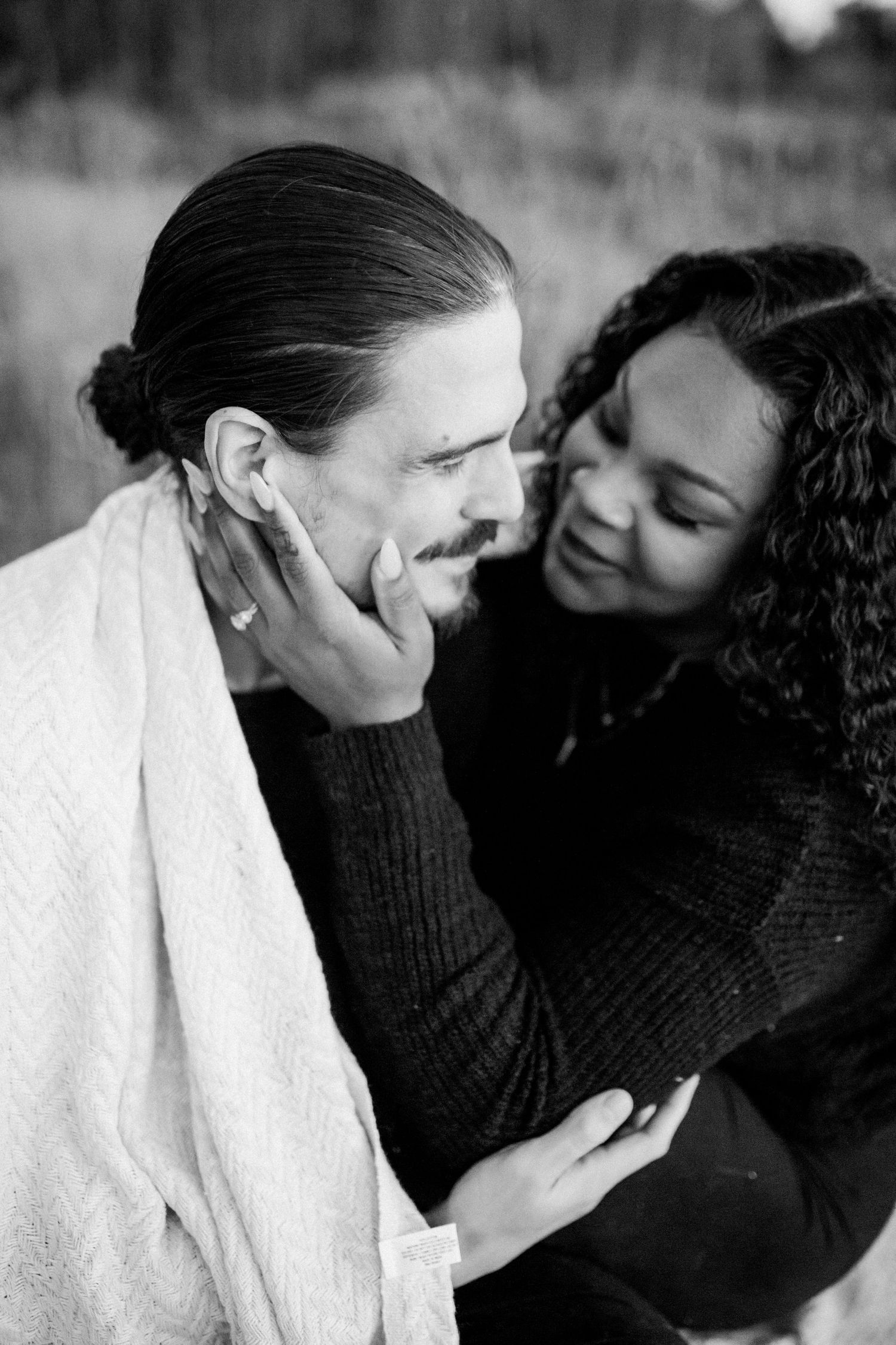 Intimate black and white portrait of couple sharing tender moment with gentle touch and warm expressions.