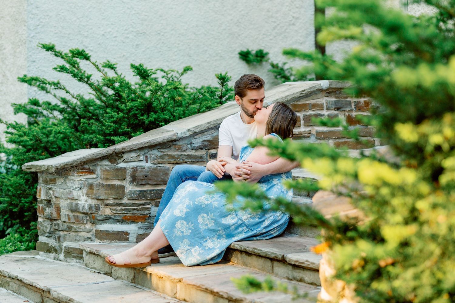 Person in blue dress lounging on stone steps in a garden setting.