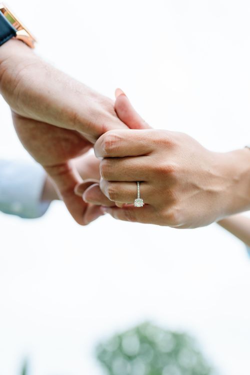 Close-up view of hands exchanging an engagement ring in a romantic proposal moment.