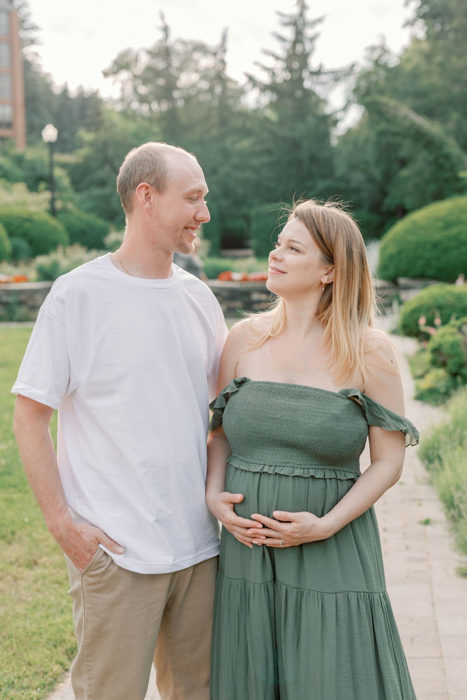 A couple in casual attire shares intimate moments while walking along a garden path.