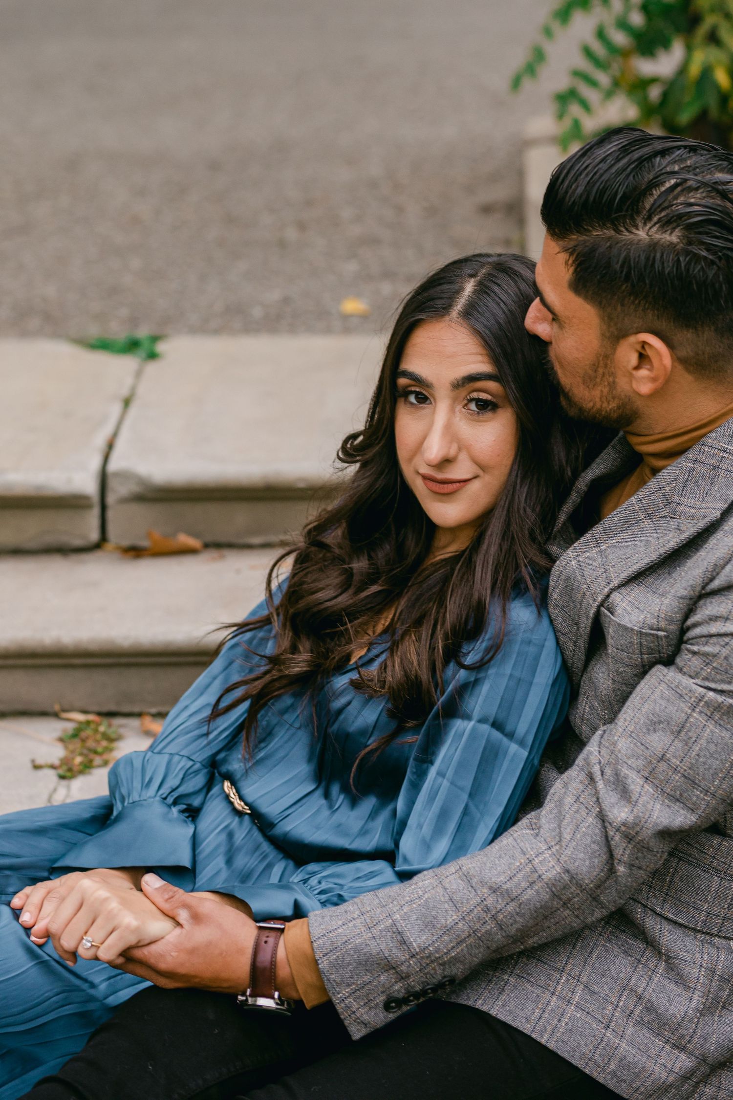 Couple sharing tender moments while sitting together outdoors in casual attire.