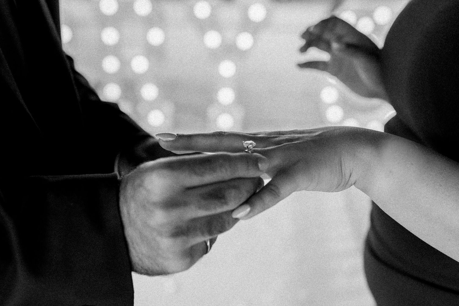 A couple shares an intimate moment at a wedding reception with bokeh lights in the background.