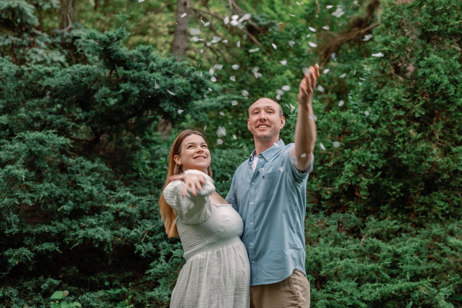 A joyful couple celebrates in a garden setting with confetti floating through the air.