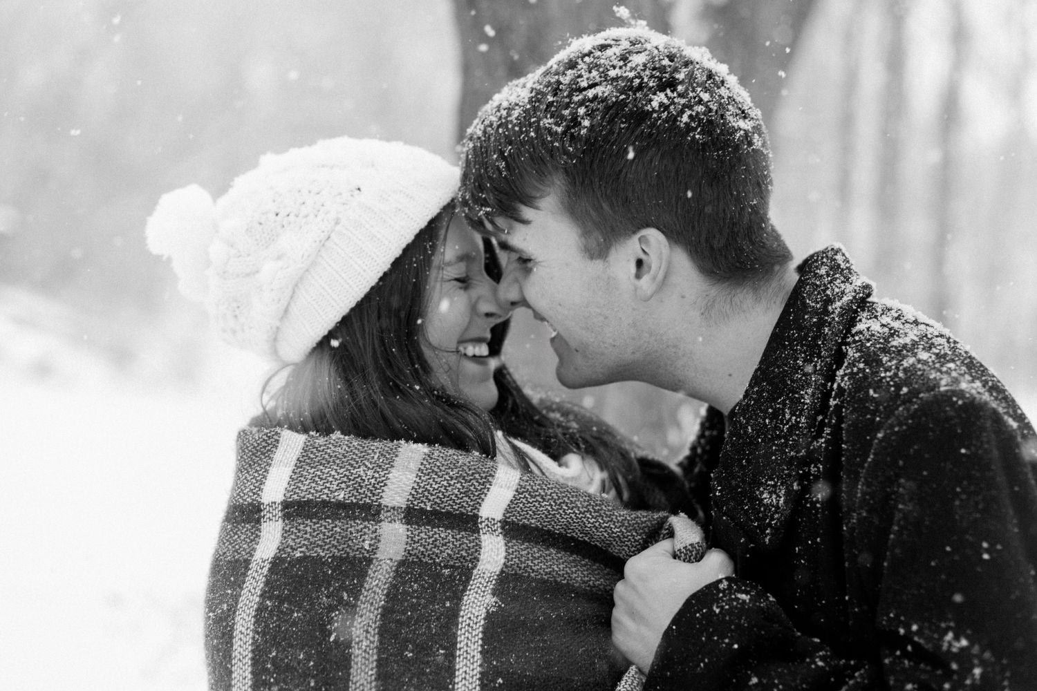 A romantic winter scene shows a couple embracing in the falling snow.