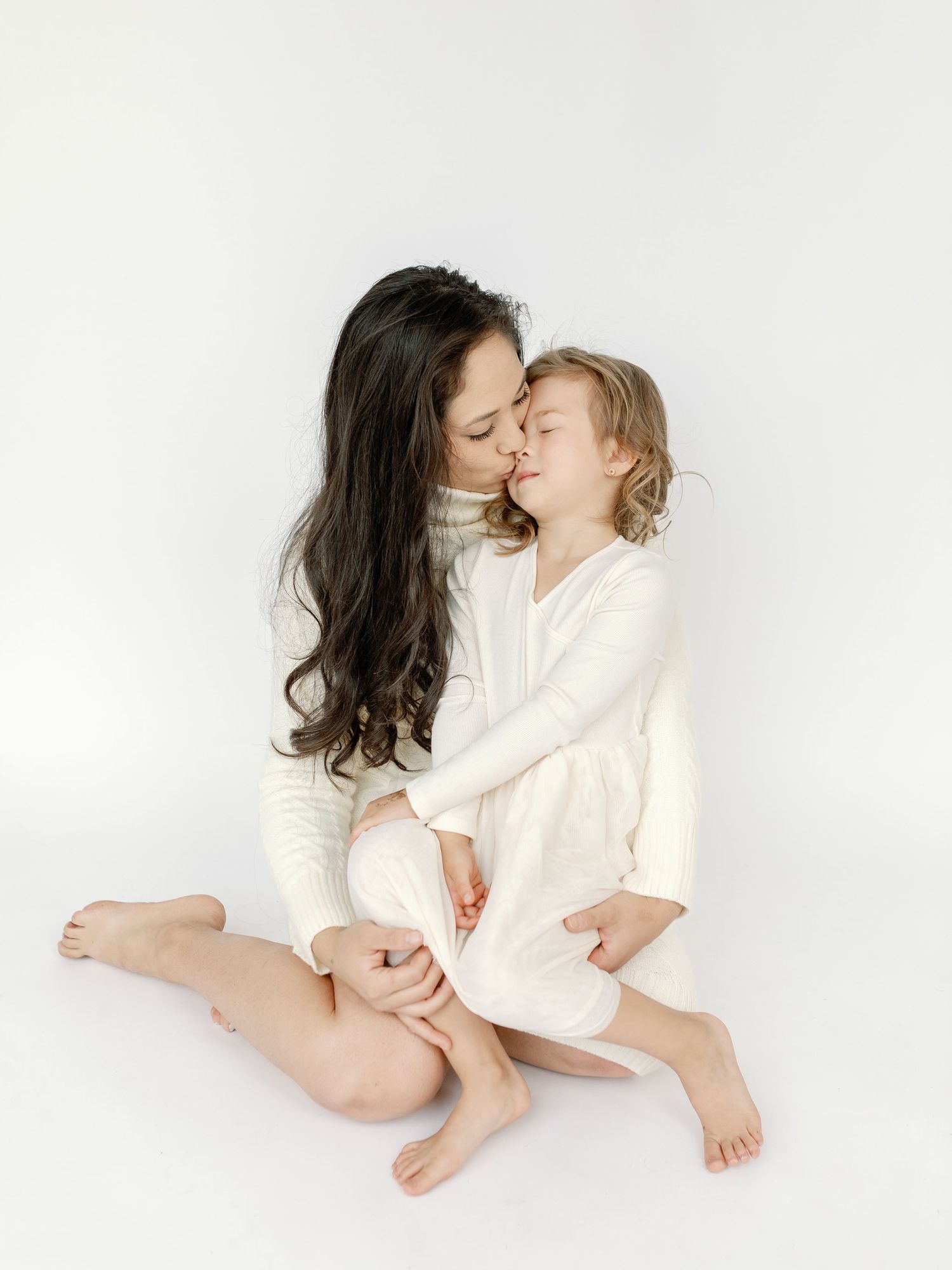 Tender black and white portrait of parent and child embracing on white background.