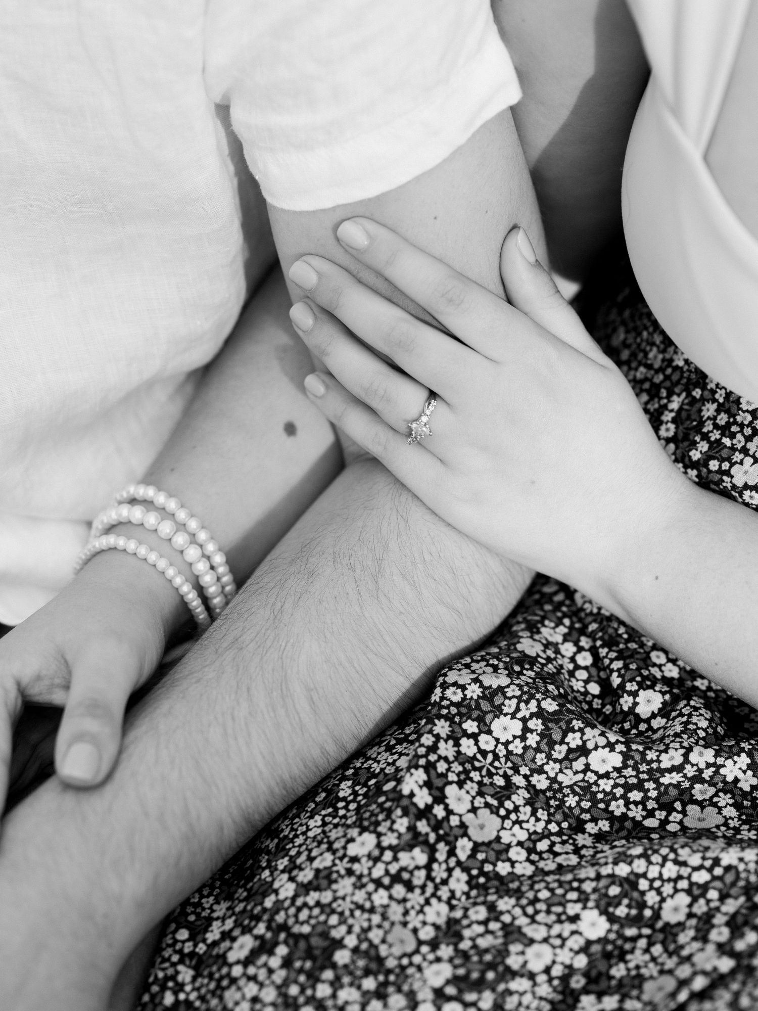 Close-up of hands with pearl bracelet against floral fabric background.