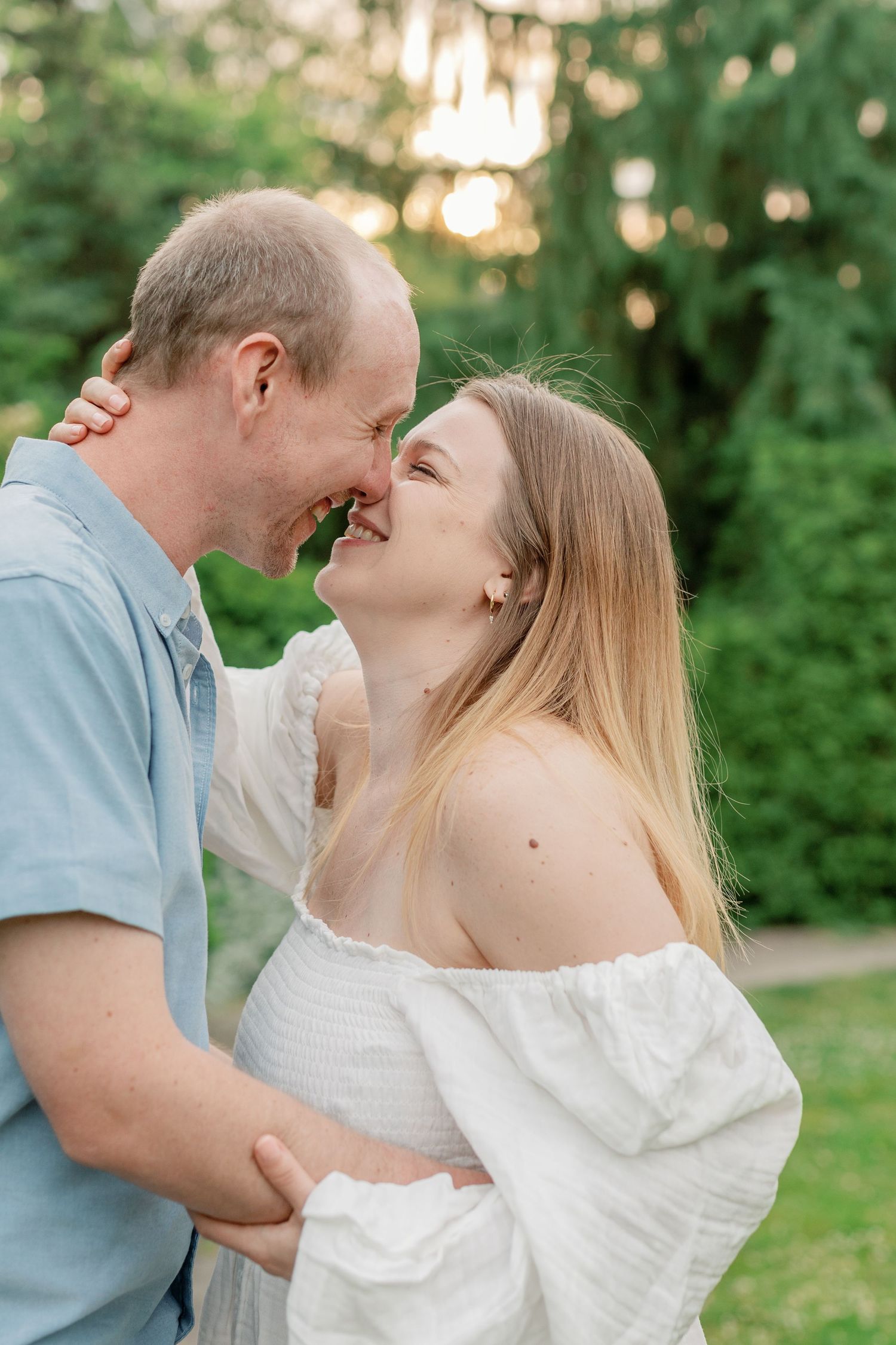 Romantic couple embracing in a garden setting during golden hour.