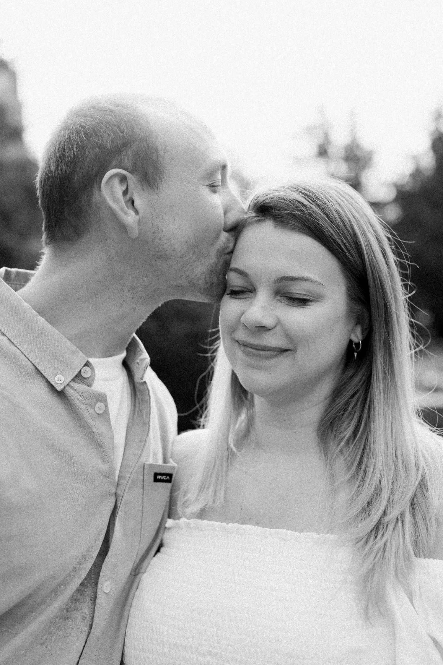 A romantic black and white portrait of a couple sharing intimate moments outdoors.