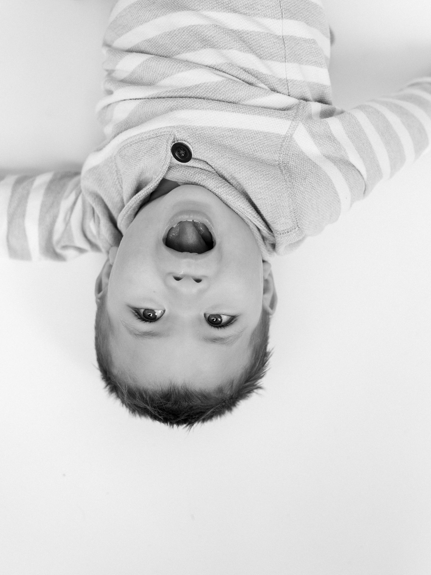 Black and white portrait of baby lying on white background.