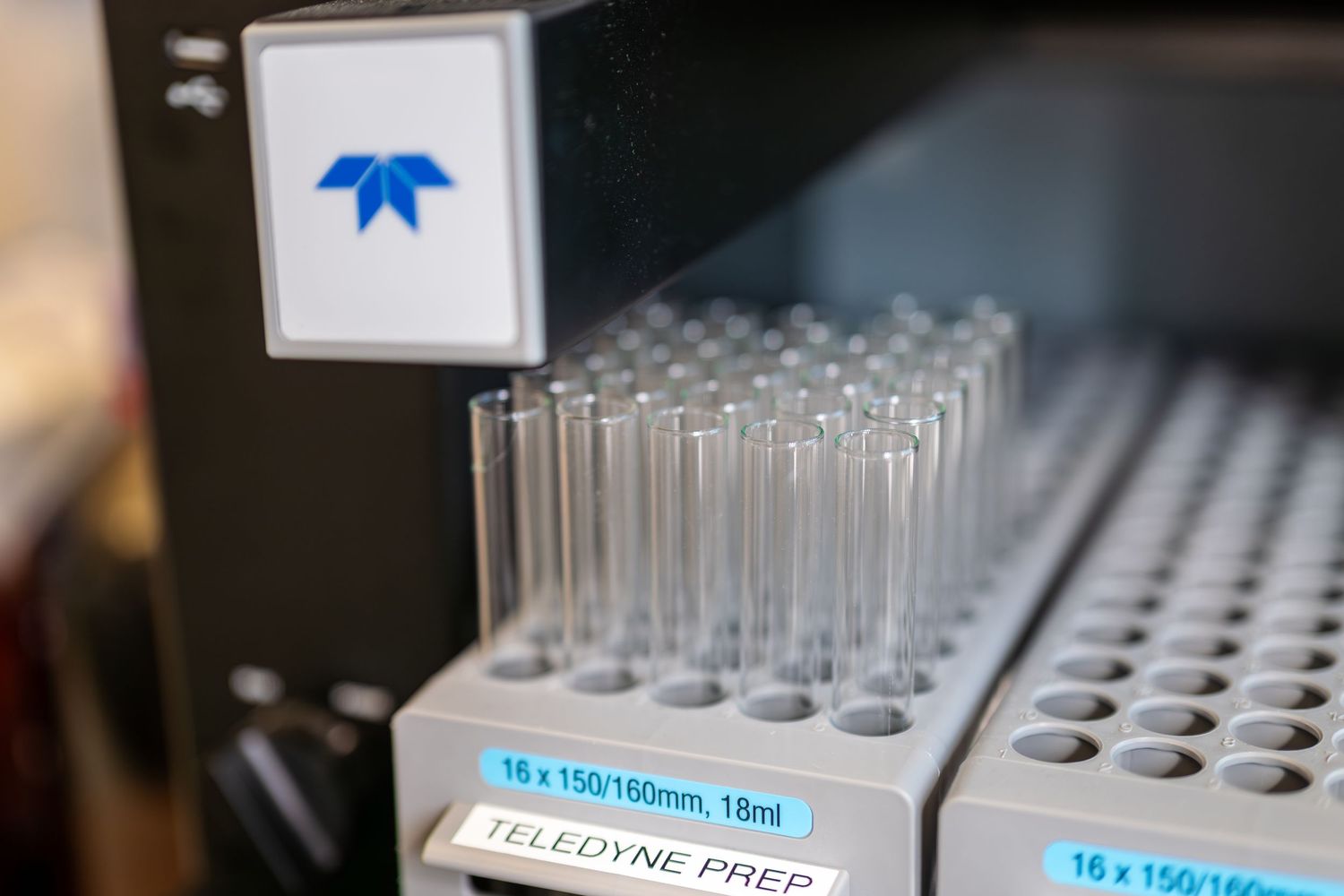 Rack of empty glass test tubes labeled 16 x 150/160mm 18ml on a Teledyne Prep laboratory automation instrument.