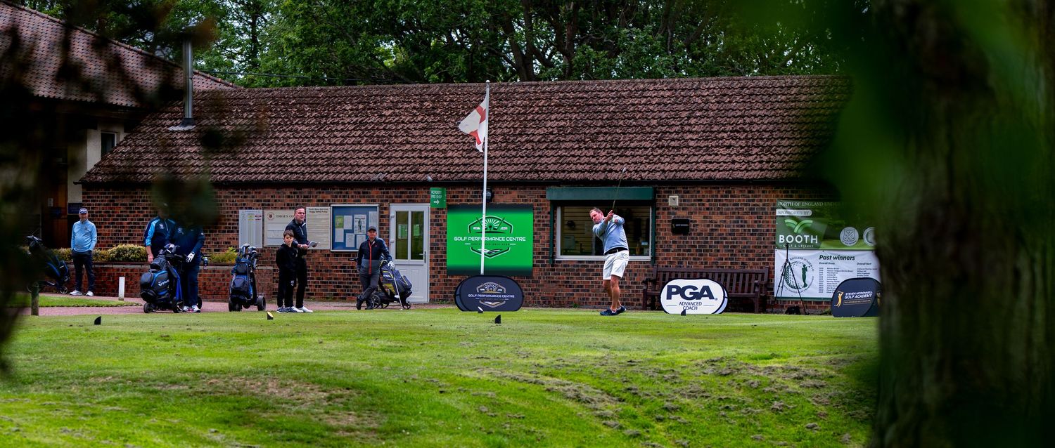 Golfers near a PGA clubhouse surrounded by lush green trees on a golf course.