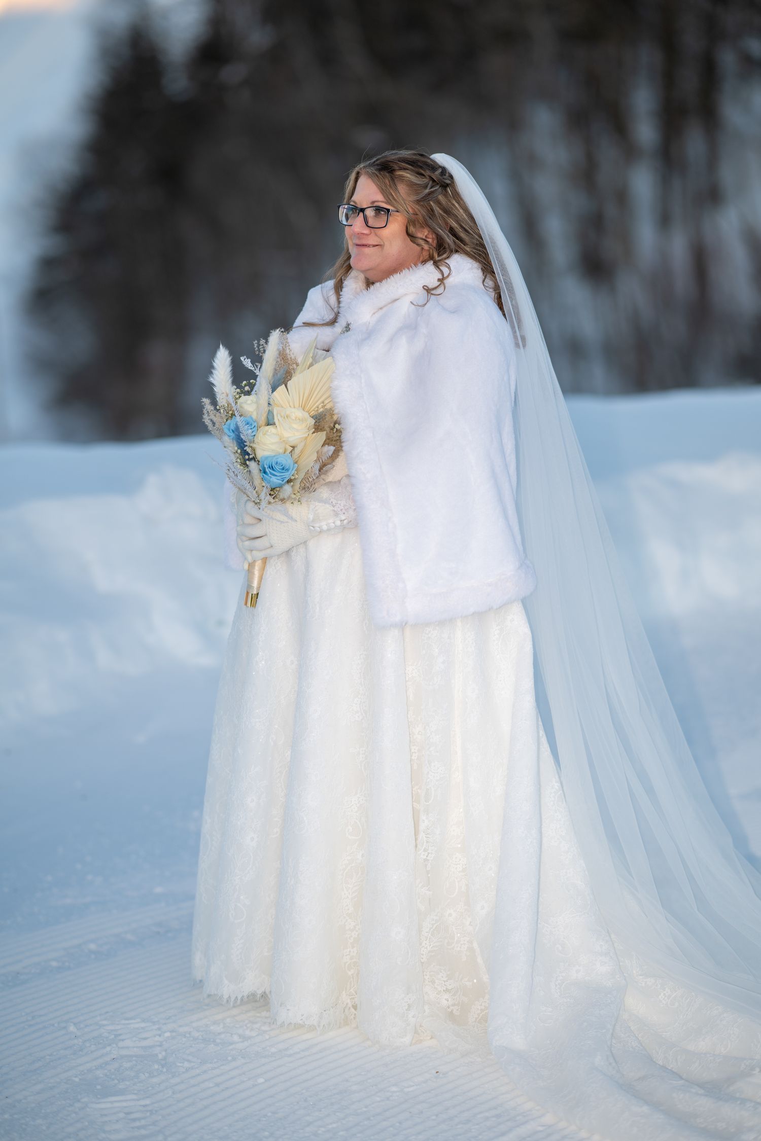 Fairytale winter bride wearing a white cloak in a snowy Quebec landscape