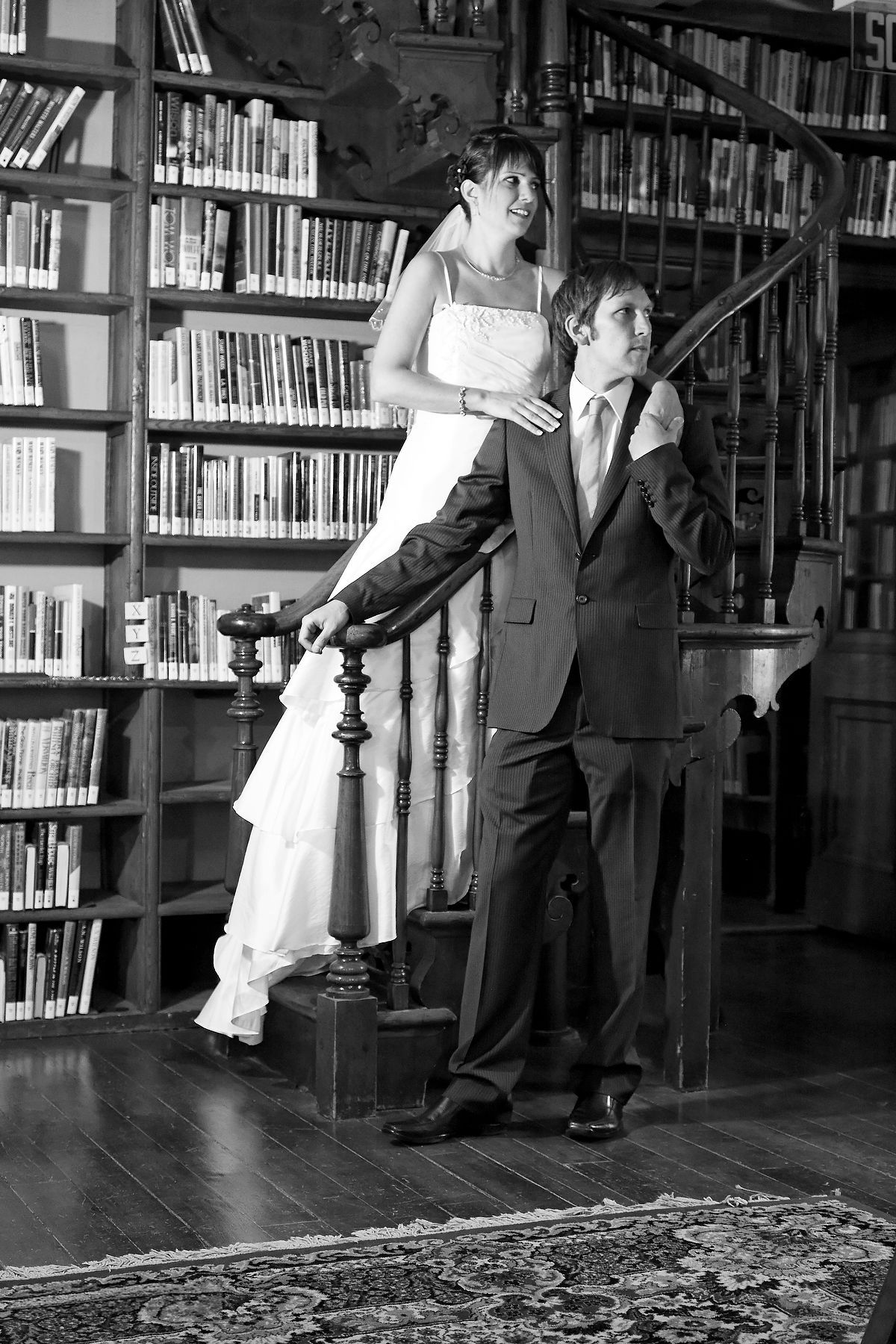 Artistic black and white wedding portrait on a grand wooden staircase in a vintage library