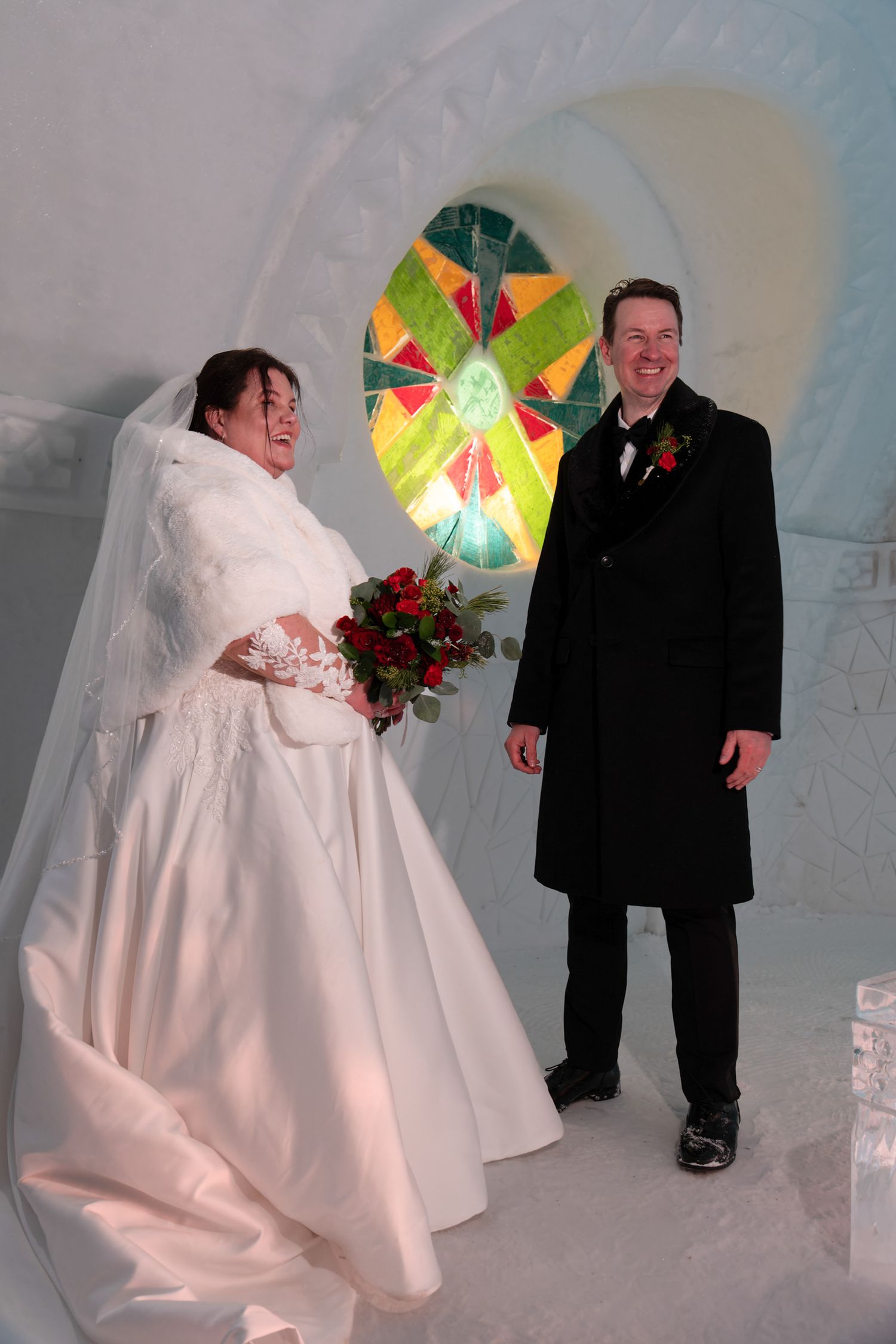 Wedding portrait in front of the colorfully patterned ice structure at the Hôtel de Glace, Quebec City
