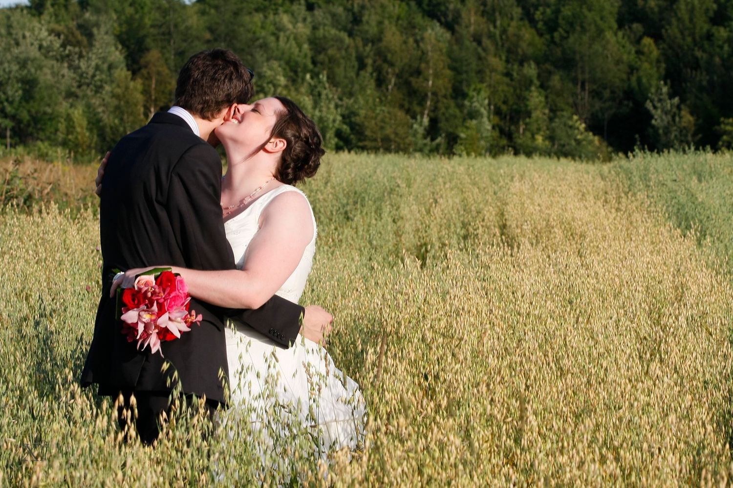 Bride and groom kissing in a golden field for a natural outdoor wedding photo