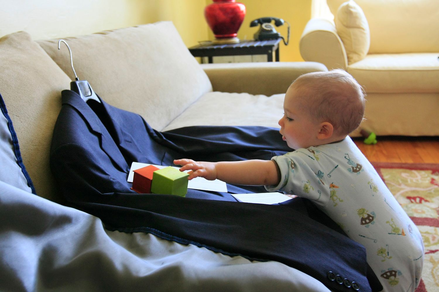 Candid morning preparation moment of a baby next to the groom's wedding suit jacket