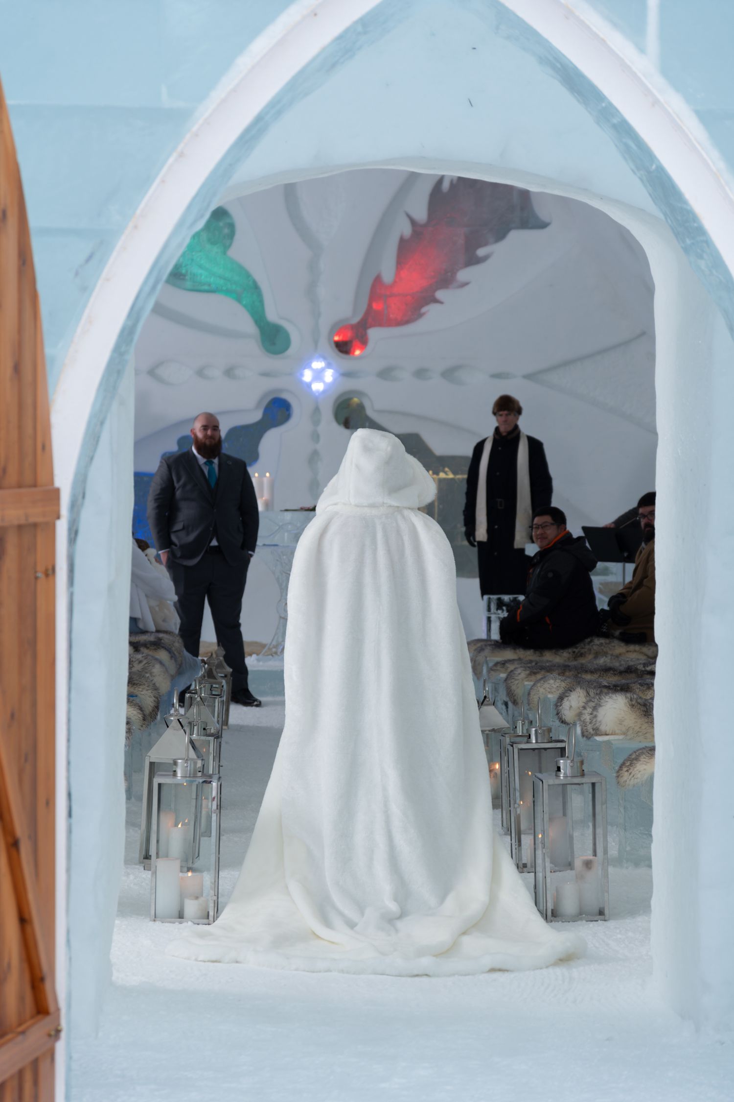 Framed perspective through an icy archway of a wedding ceremony inside the Hôtel de Glace, Quebec