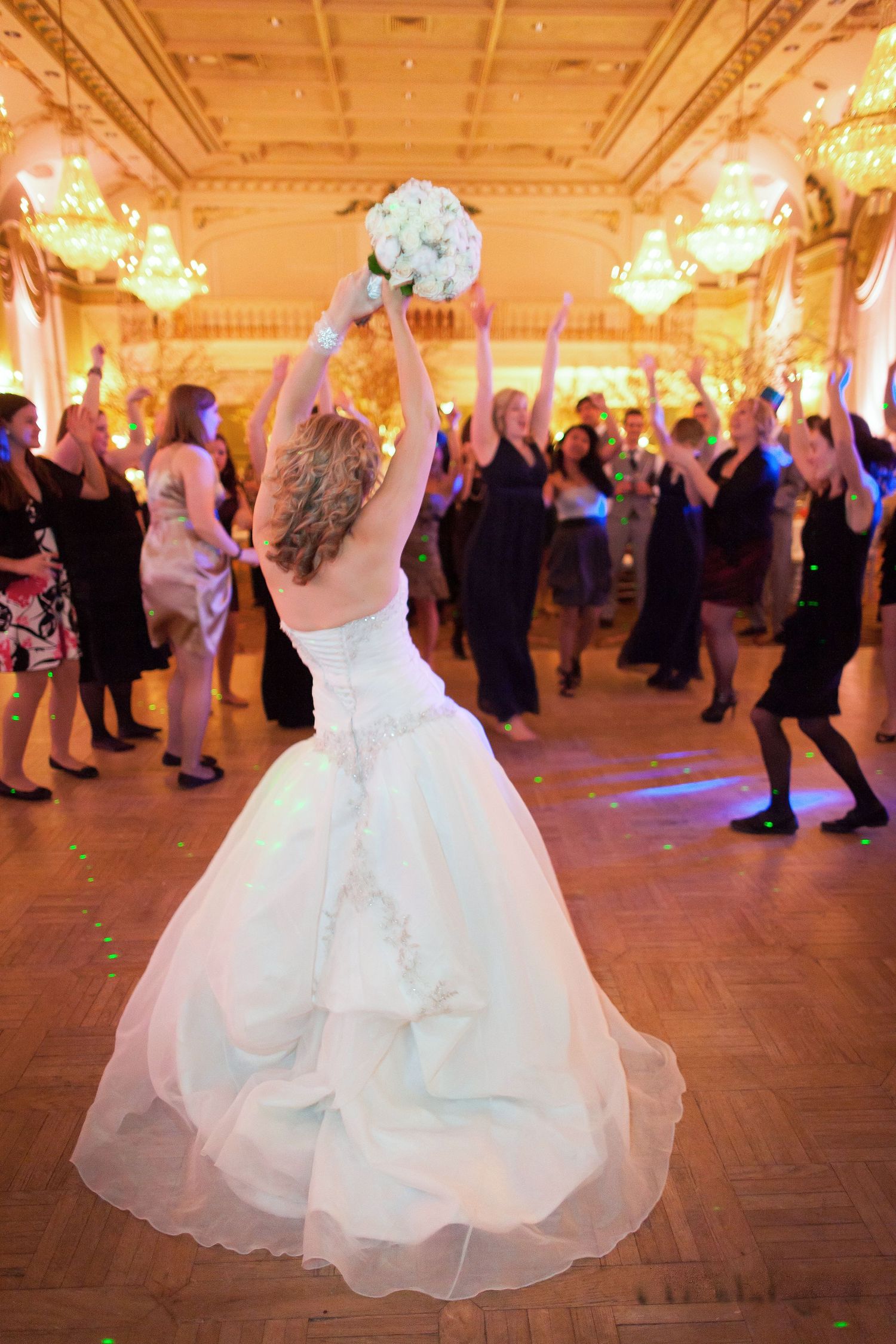 Bride celebrating in a grand ballroom and throwing the bouquet, featuring a joyful Quebec reception