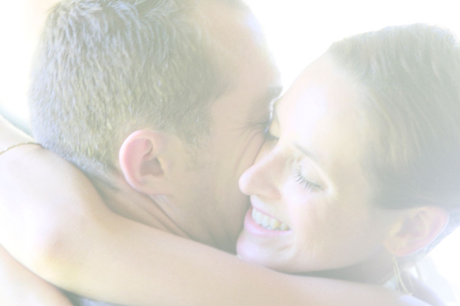 High-key close-up portrait of a bride and groom embracing