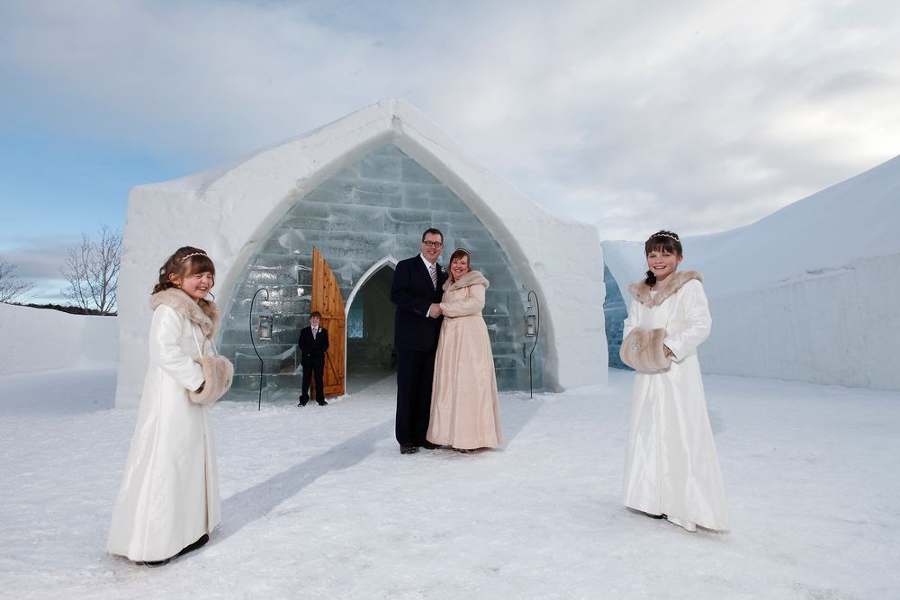 A wedding party posing outside the monumental ice entrance of the Hôtel de Glace in Quebec
