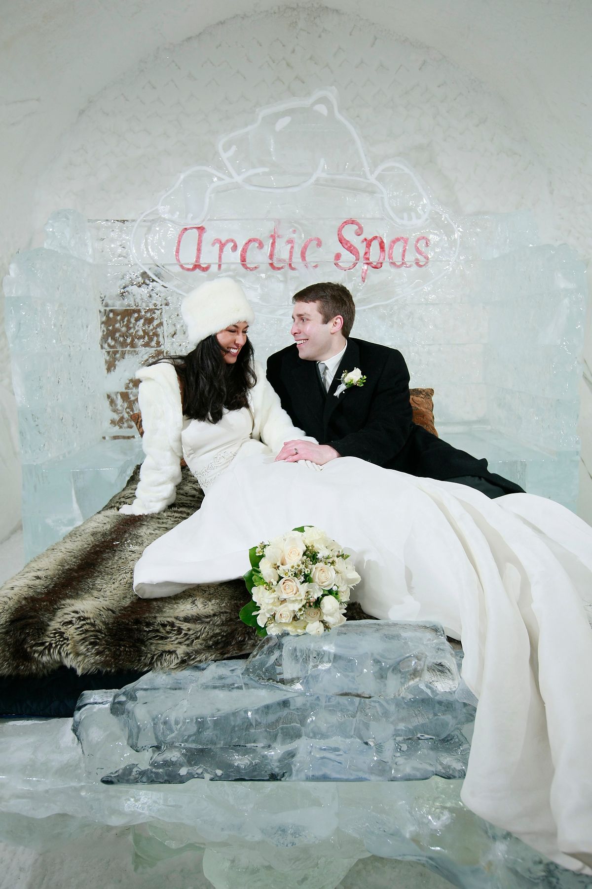 Bride and groom on a fur-lined ice throne with the Hôtel de Glace, Arctic Spa, branding