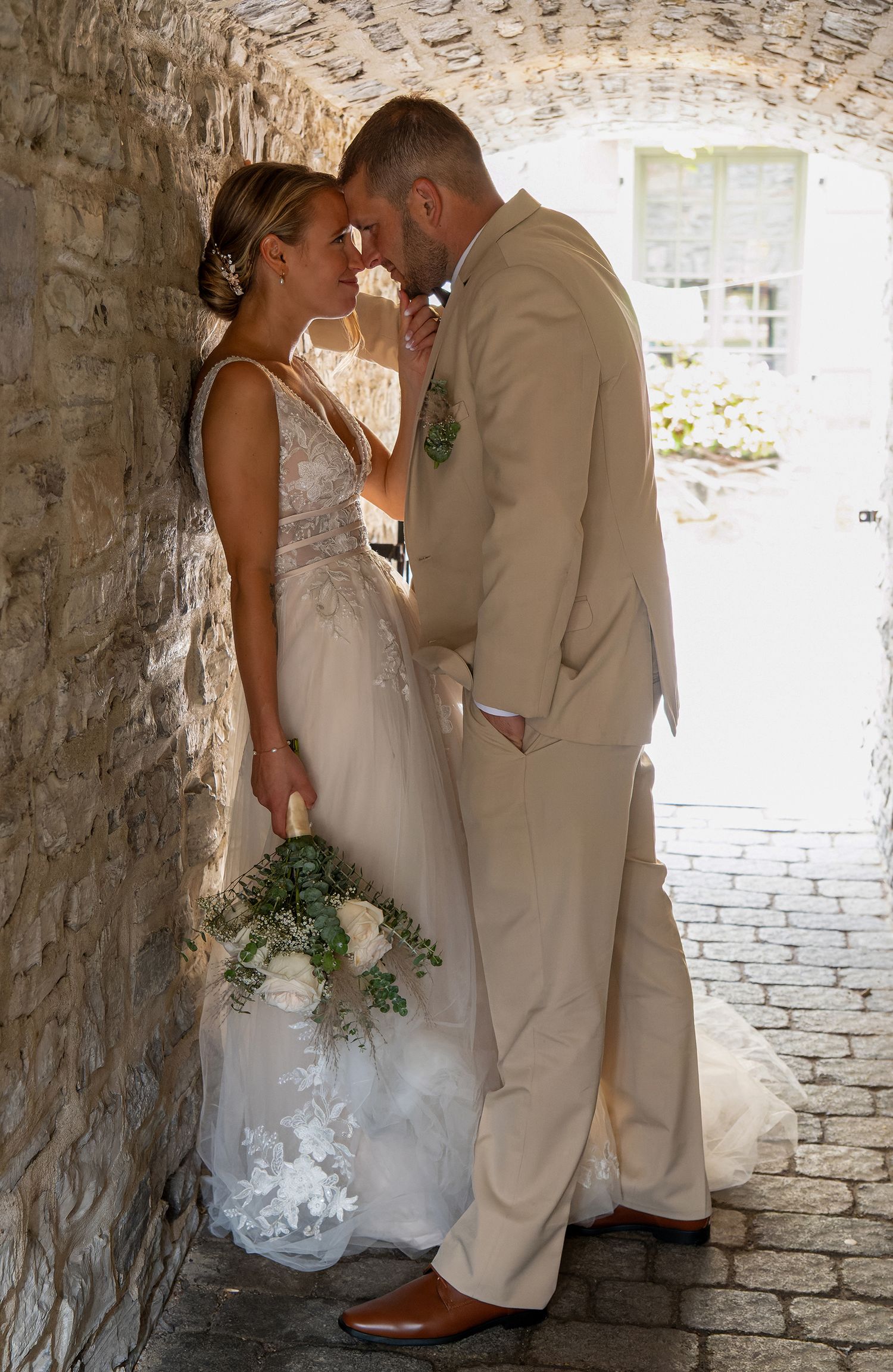 Intimate bridal couple portrait leaning against a historic stone wall in an Old Quebec alleyway