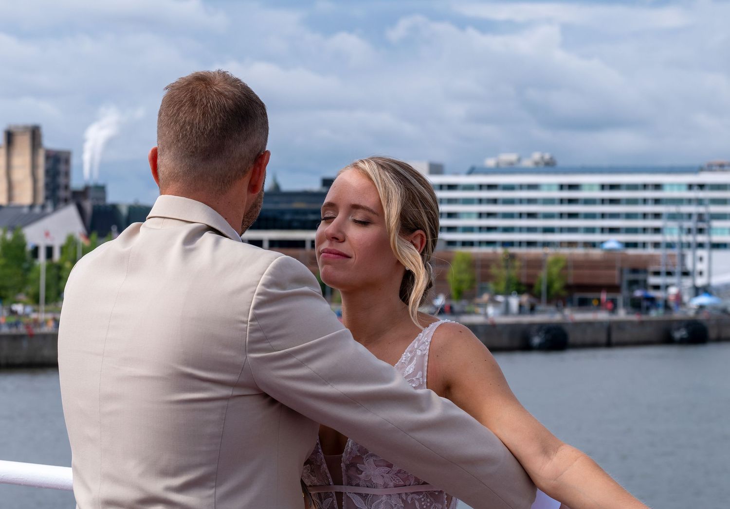 An intimate close-up wedding portrait of a bride and groom embracing with a blurred city skyline background