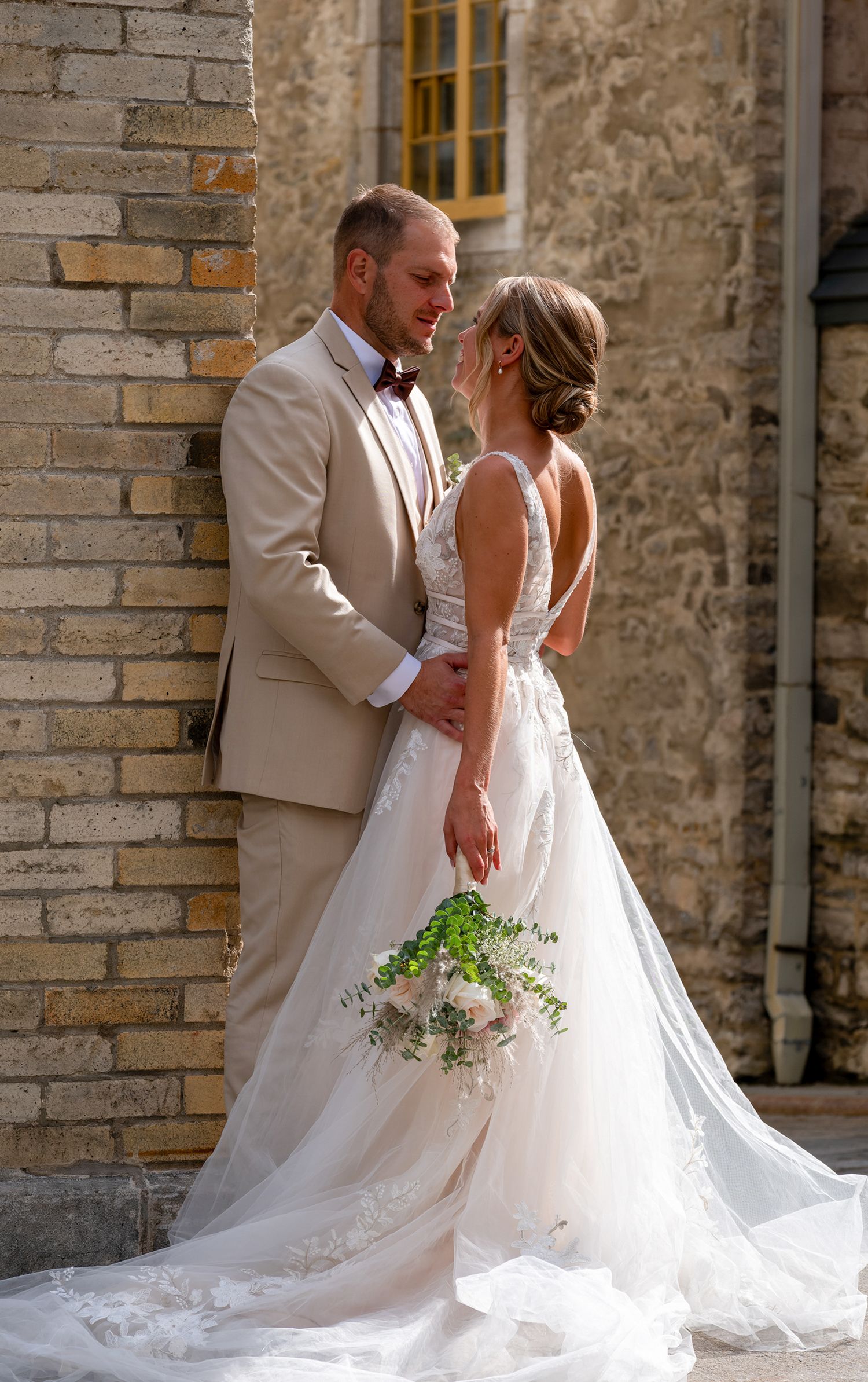 Close-up portrait of a bride and groom embracing against an old stone building in Vieux-Québec