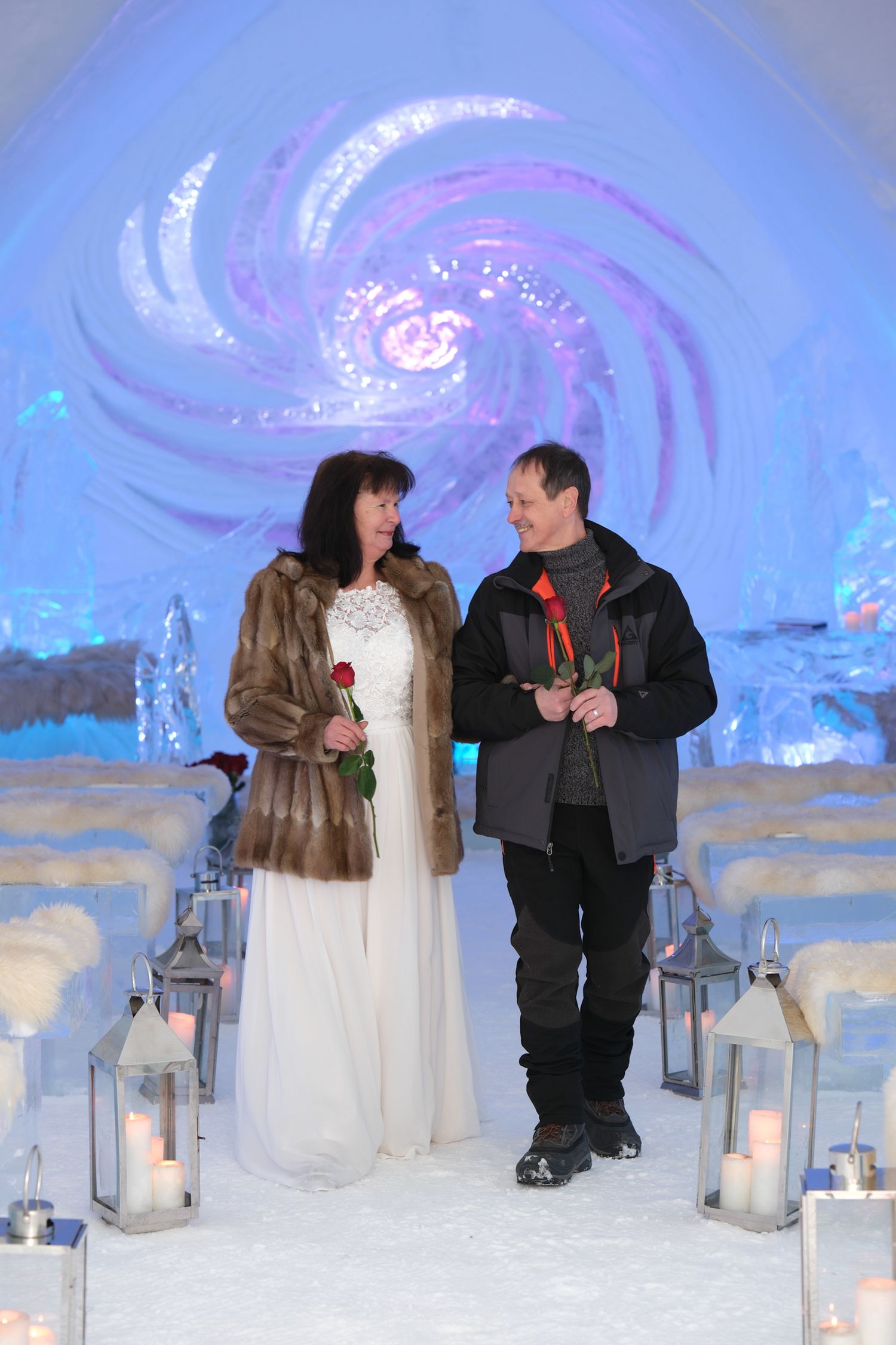 Bride and groom walking down the aisle surrounded by candlelit ice sculptures at the Hôtel de Glace chapel
